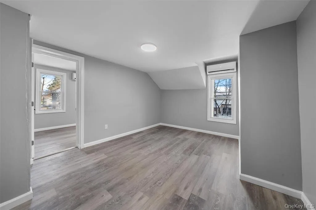 Spacious room featuring wood-finish flooring, light gray wall paint, and white trim Spacious room featuring wood-finish flooring, light gray wall paint, and white trim