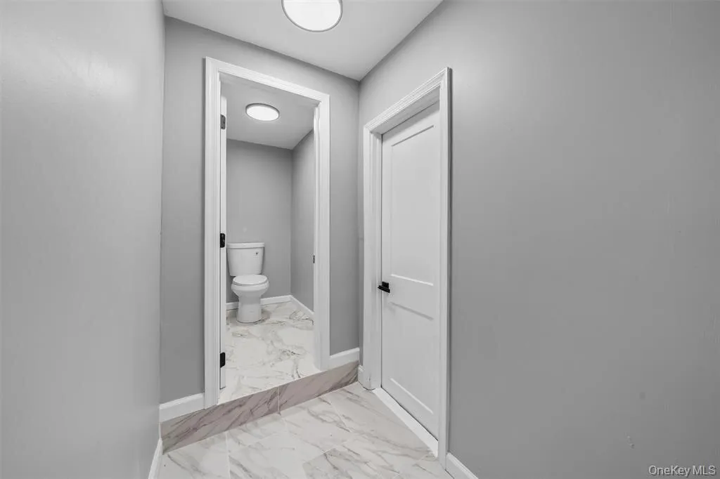 Hallway featuring light gray walls, recessed ceiling lighting, and a door with black hardware Hallway featuring light gray walls, recessed ceiling lighting, and a door with black hardware