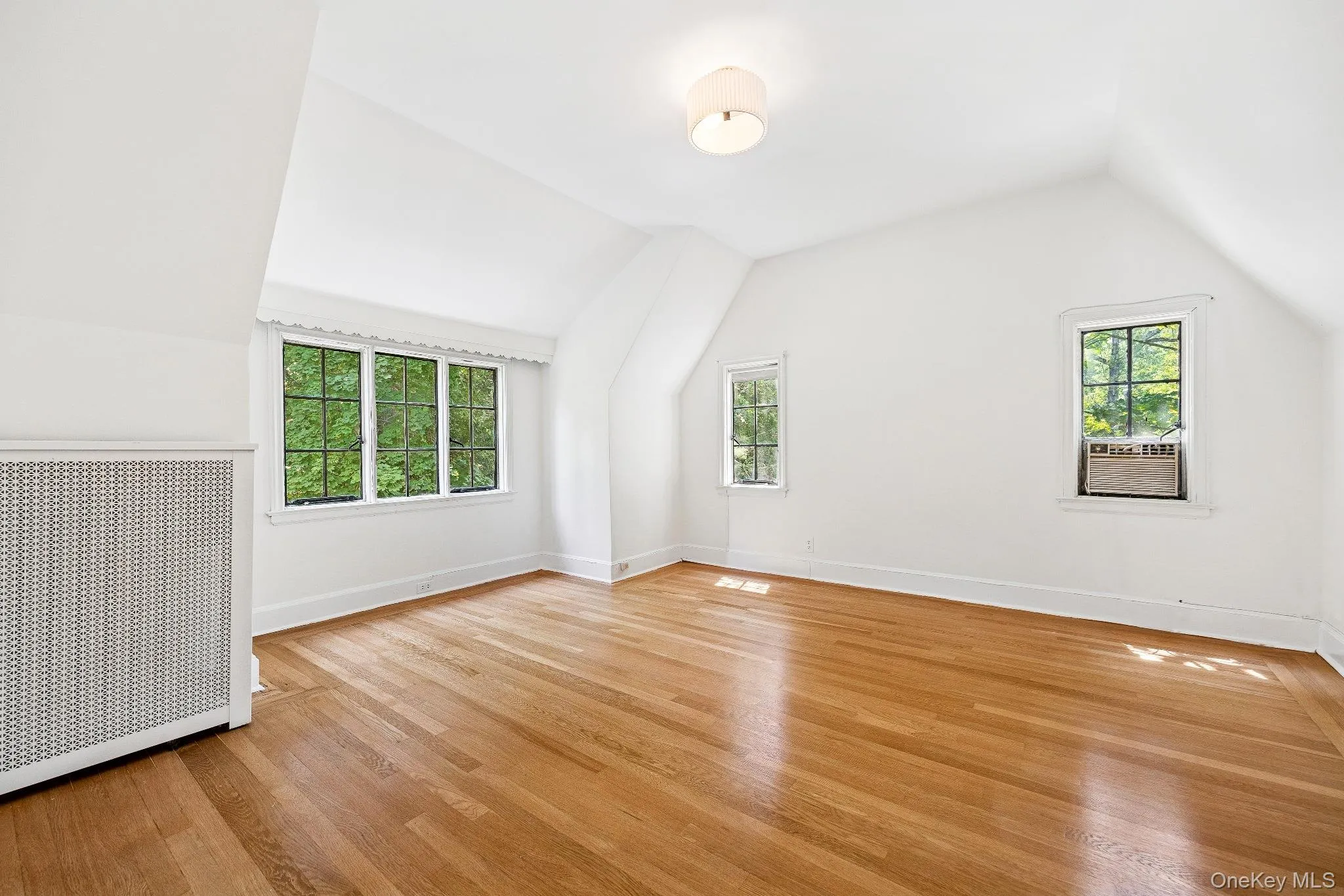 Additional bedroom in attic l featuring lofted ceiling, radiator heating unit, and light wood-style floors Additional bedroom in attic l featuring lofted ceiling, radiator heating unit, and light wood-style floors