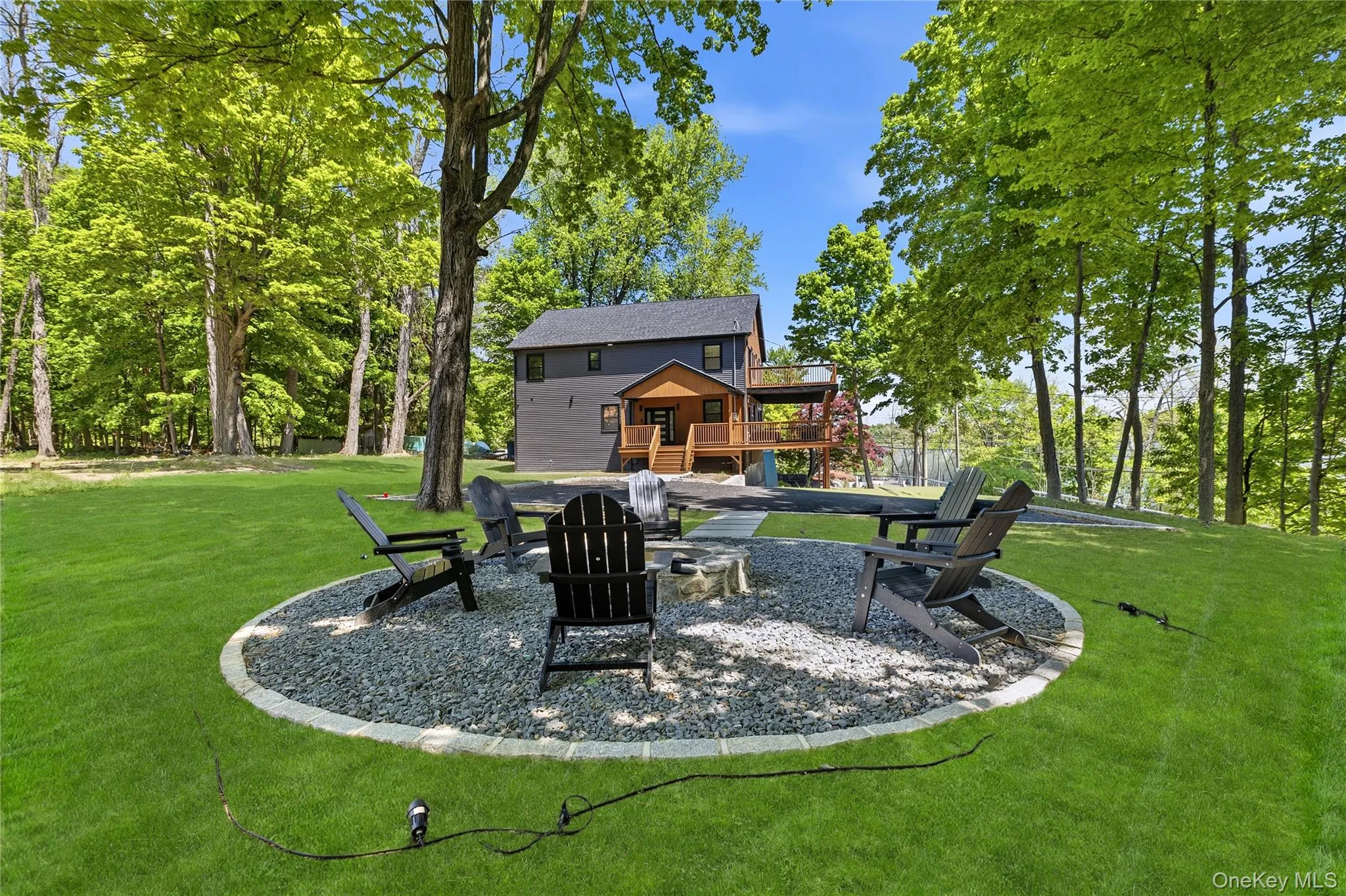 Expansive lawn area featuring a circular gravel fire pit with a stone border Expansive lawn area featuring a circular gravel fire pit with a stone border