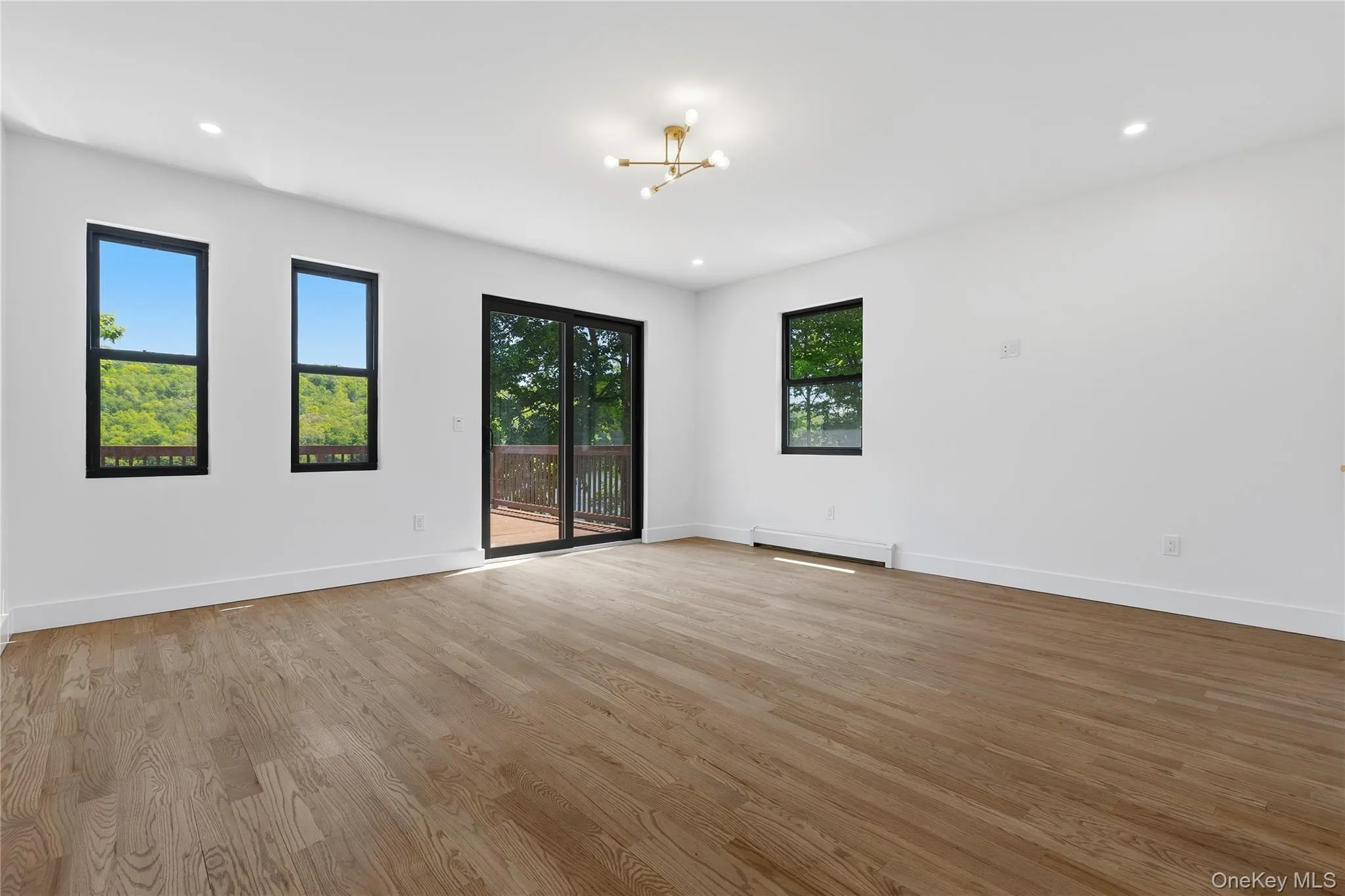 Spacious room featuring wood-finish flooring, white walls, and recessed lighting Spacious room featuring wood-finish flooring, white walls, and recessed lighting