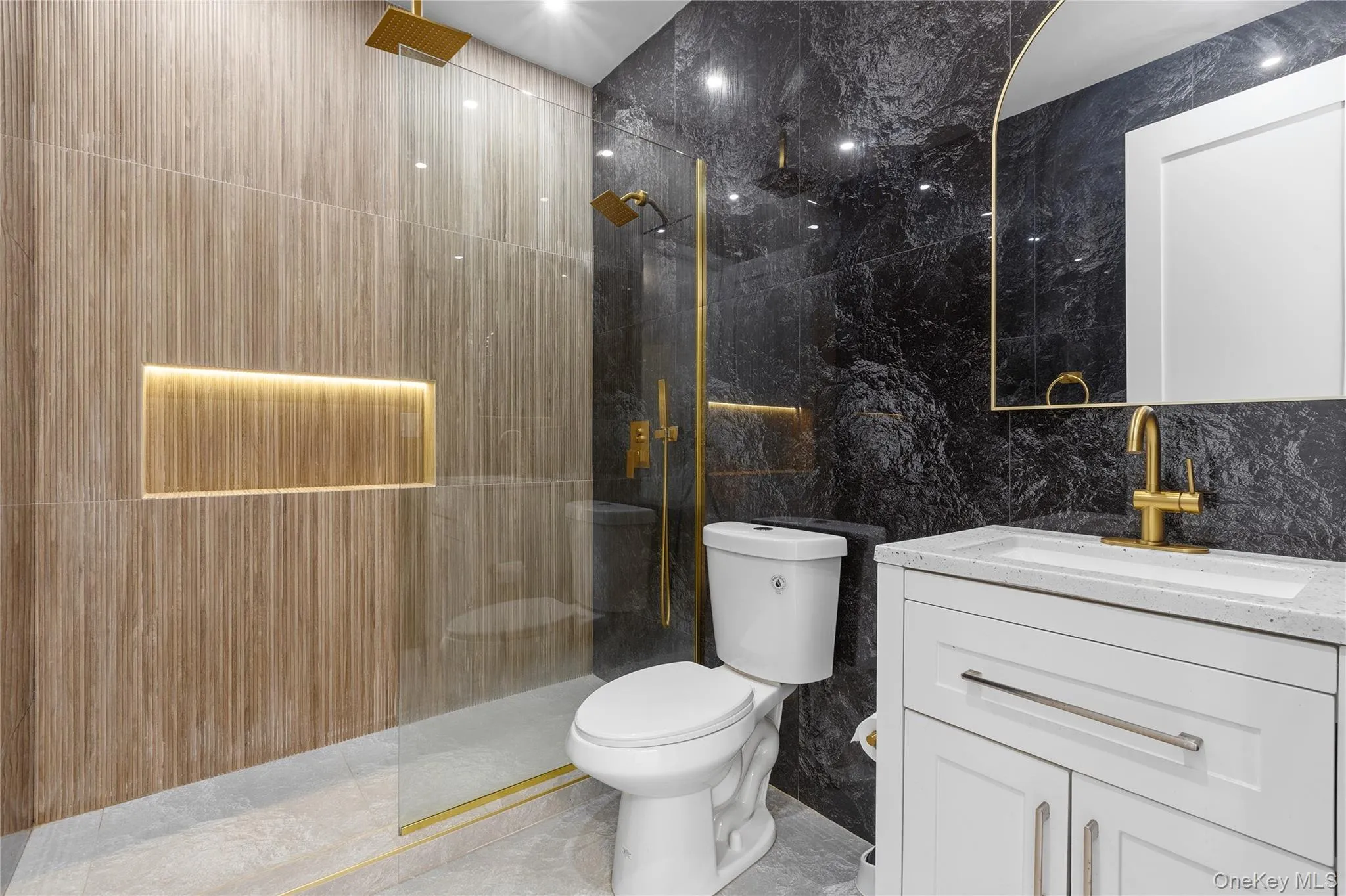 Modern bathroom featuring a glass-enclosed shower with gold-tone fixtures, wood-finish wall tiling, and an illuminated shower niche Modern bathroom featuring a glass-enclosed shower with gold-tone fixtures, wood-finish wall tiling, and an illuminated shower niche