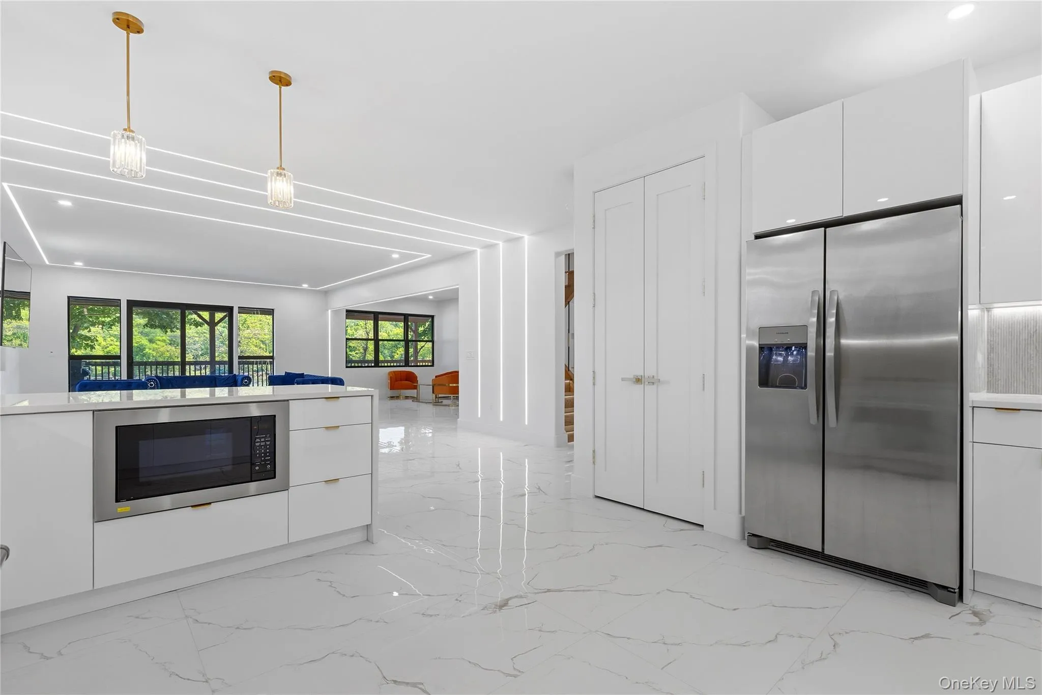 Modern kitchen featuring white cabinetry, a stainless steel side-by-side refrigerator, a built-in microwave, and white porcelain flooring Modern kitchen featuring white cabinetry, a stainless steel side-by-side refrigerator, a built-in microwave, and white porcelain flooring