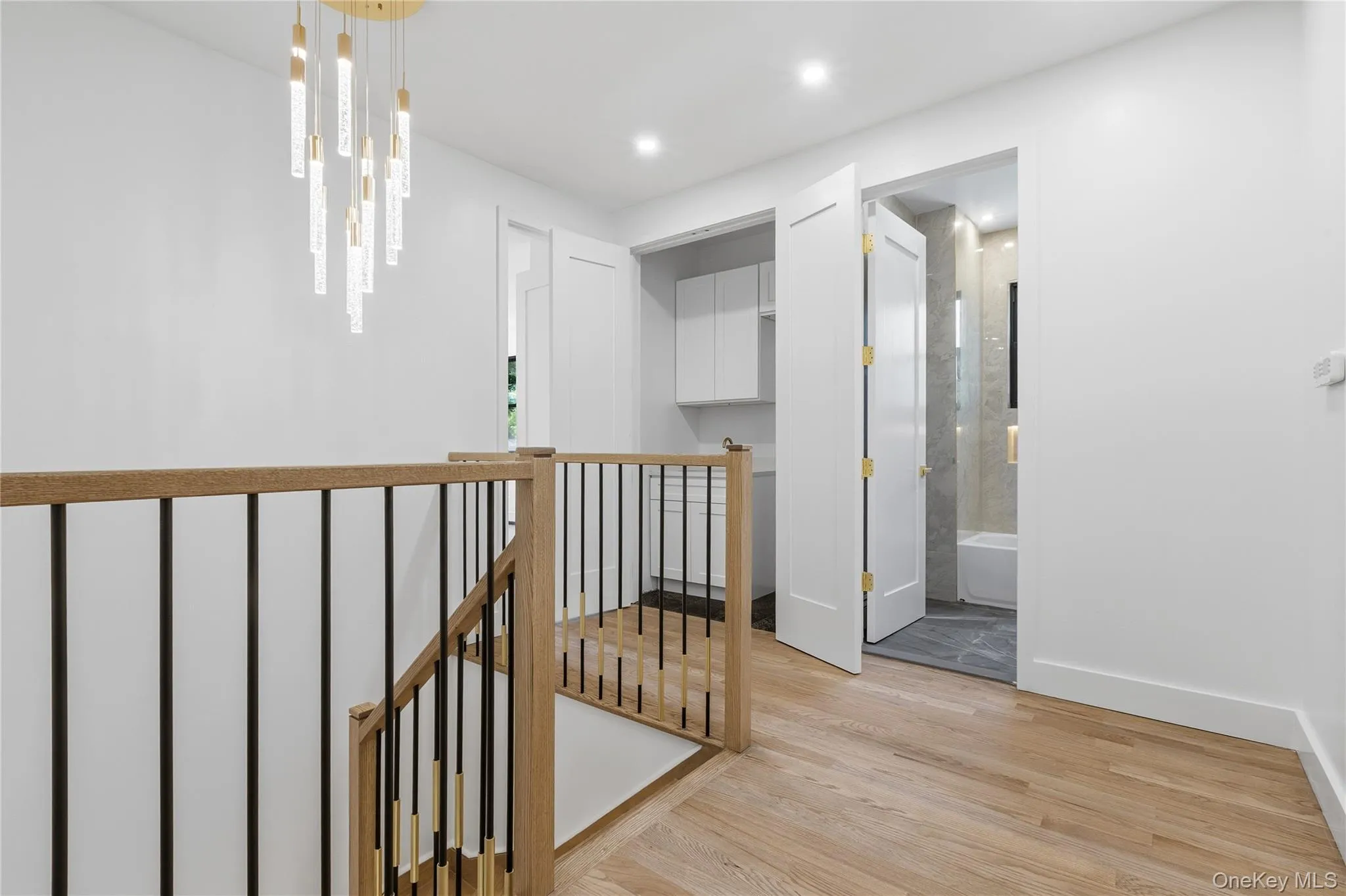 Hardwood flooring throughout a bright hallway with a modern chandelier Hardwood flooring throughout a bright hallway with a modern chandelier