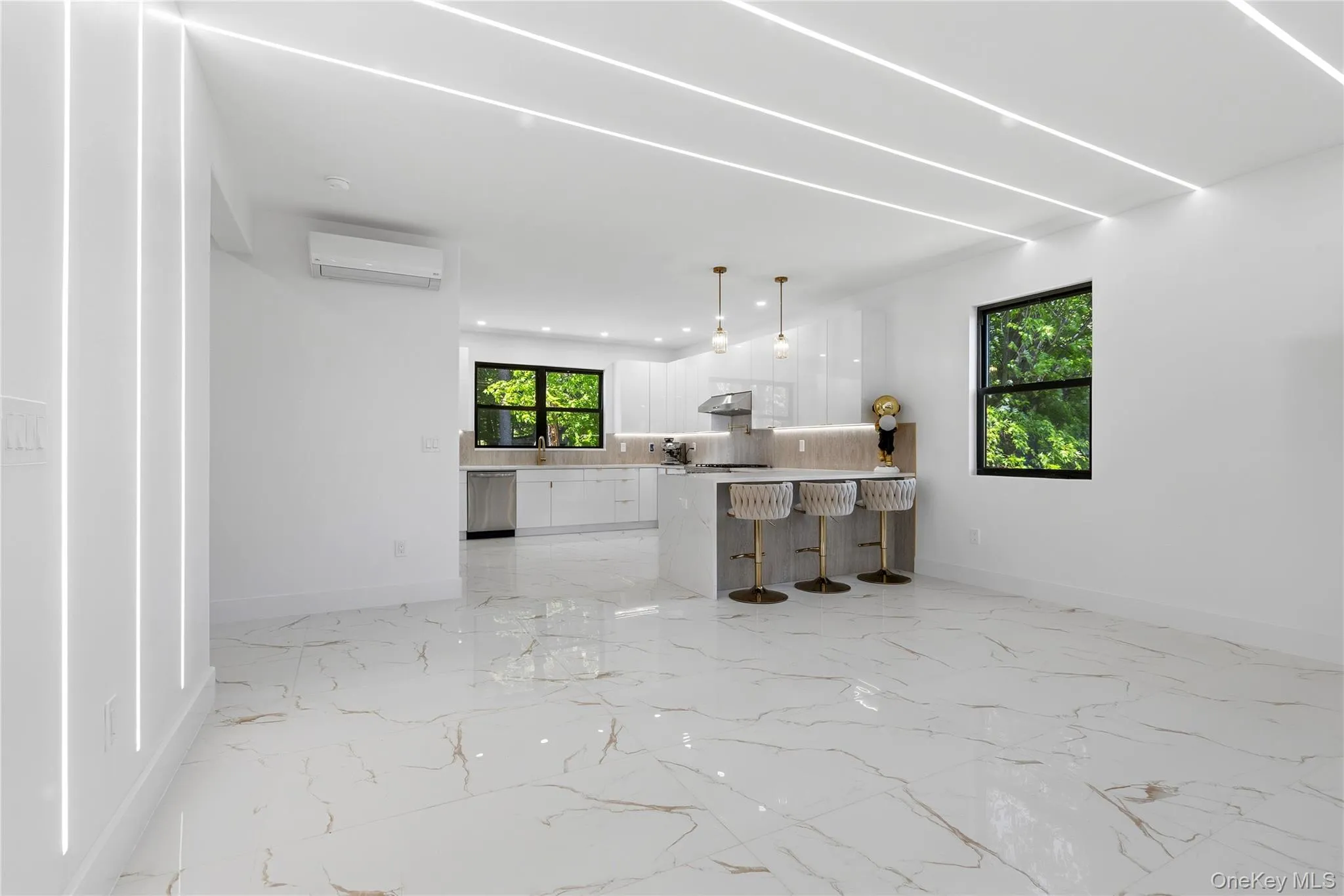 Open-concept living space featuring high-gloss marbled flooring, recessed linear ceiling lighting, and a modern kitchen with a waterfall island Open-concept living space featuring high-gloss marbled flooring, recessed linear ceiling lighting, and a modern kitchen with a waterfall island
