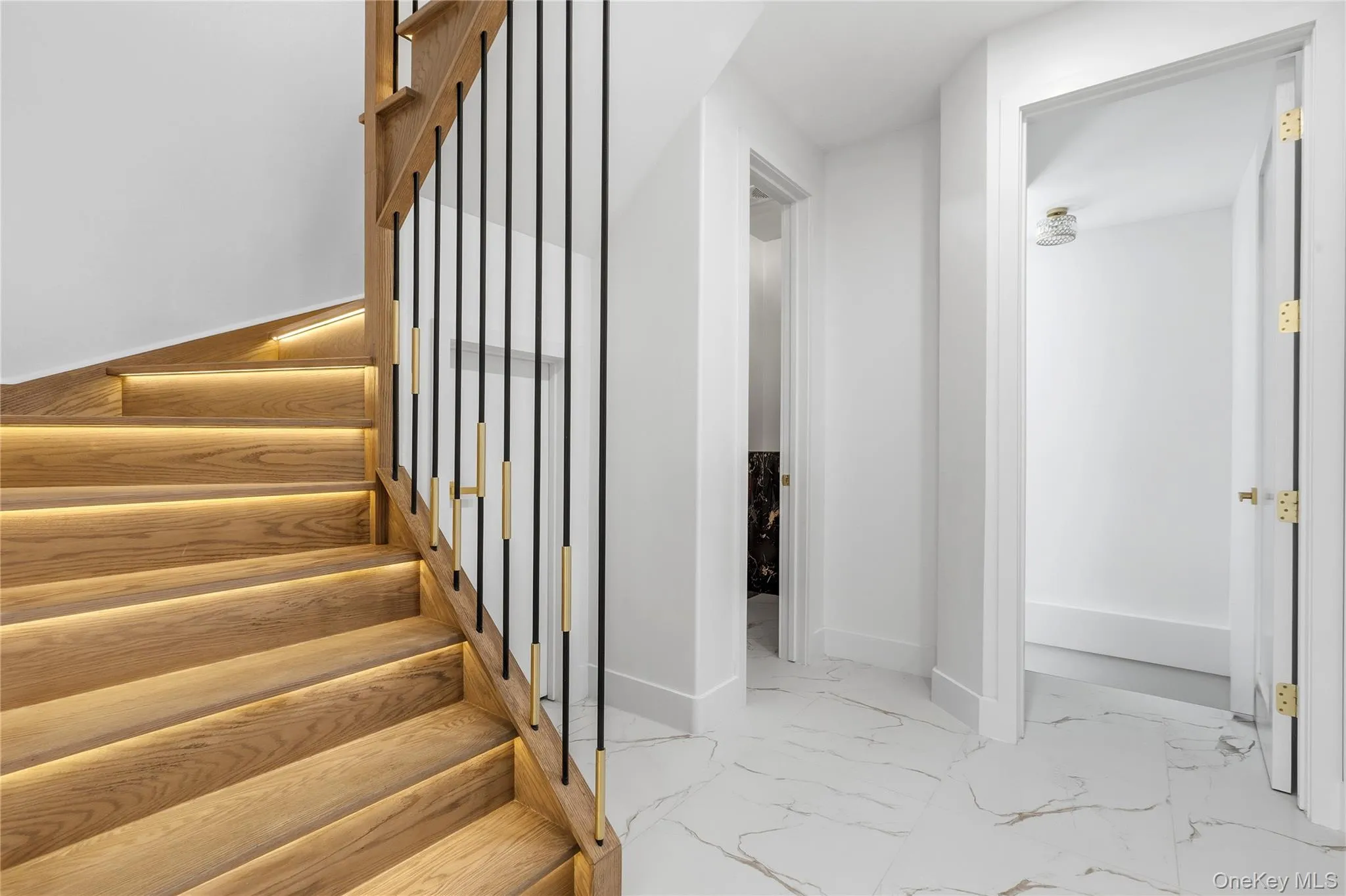 Hardwood staircase with integrated step lighting and contemporary black and brass balusters Hardwood staircase with integrated step lighting and contemporary black and brass balusters