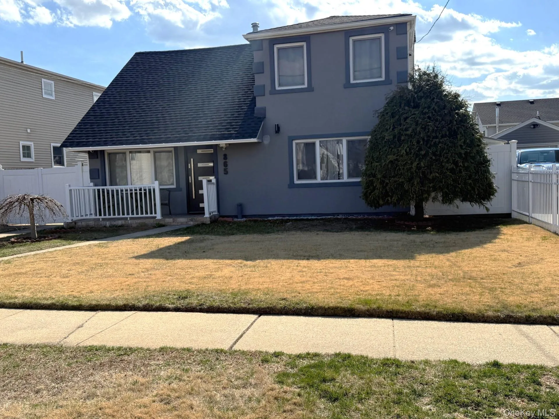Traditional-style house with stucco siding, fence, a front lawn, and roof with shingles Traditional-style house with stucco siding, fence, a front lawn, and roof with shingles