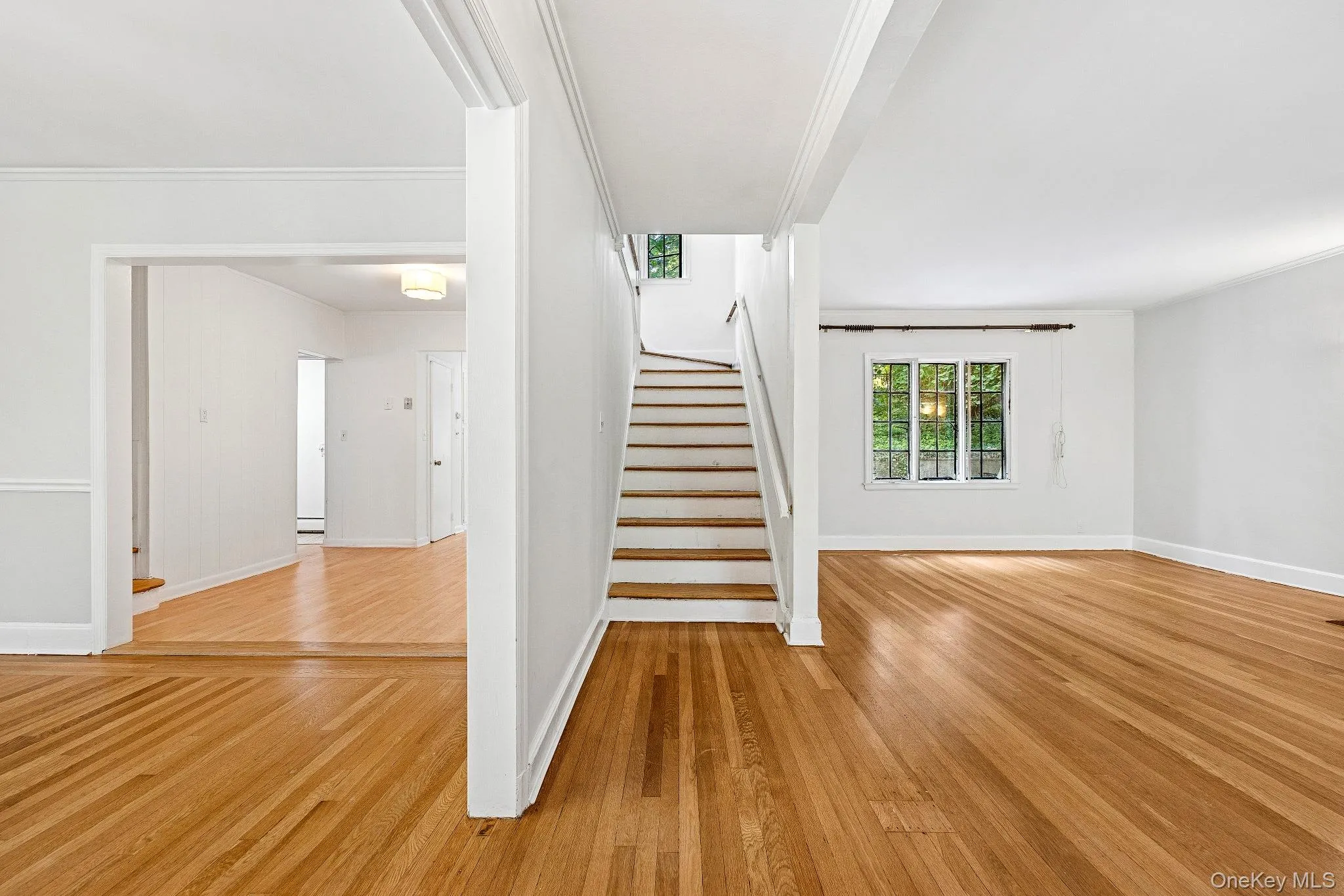Stairway featuring wood finished floors and crown molding Stairway featuring wood finished floors and crown molding