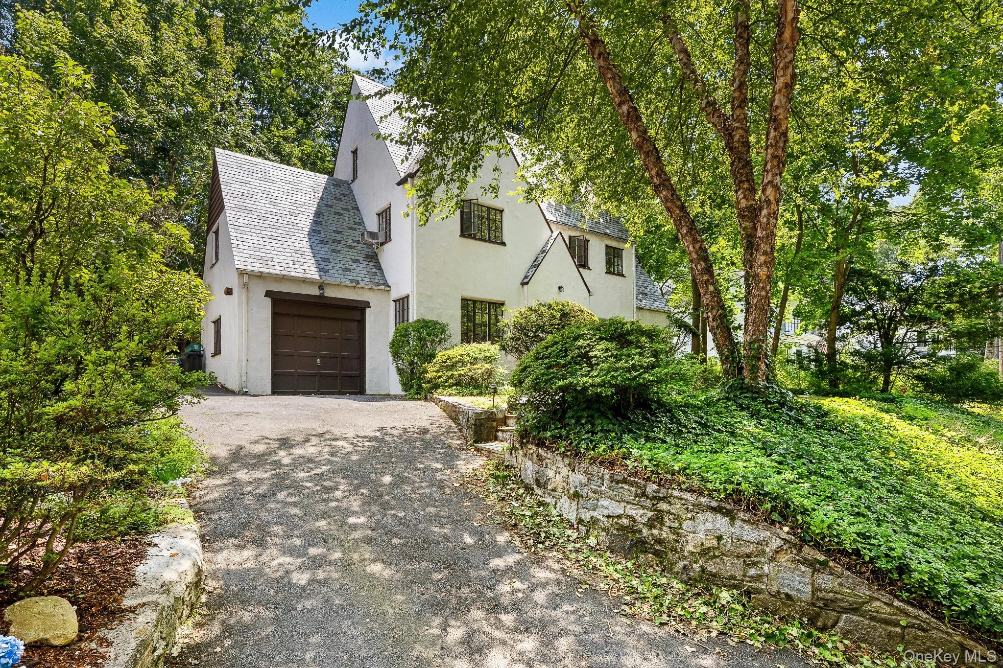 View of front of home featuring asphalt driveway, a high end roof, stucco siding, and an attached garage View of front of home featuring asphalt driveway, a high end roof, stucco siding, and an attached garage