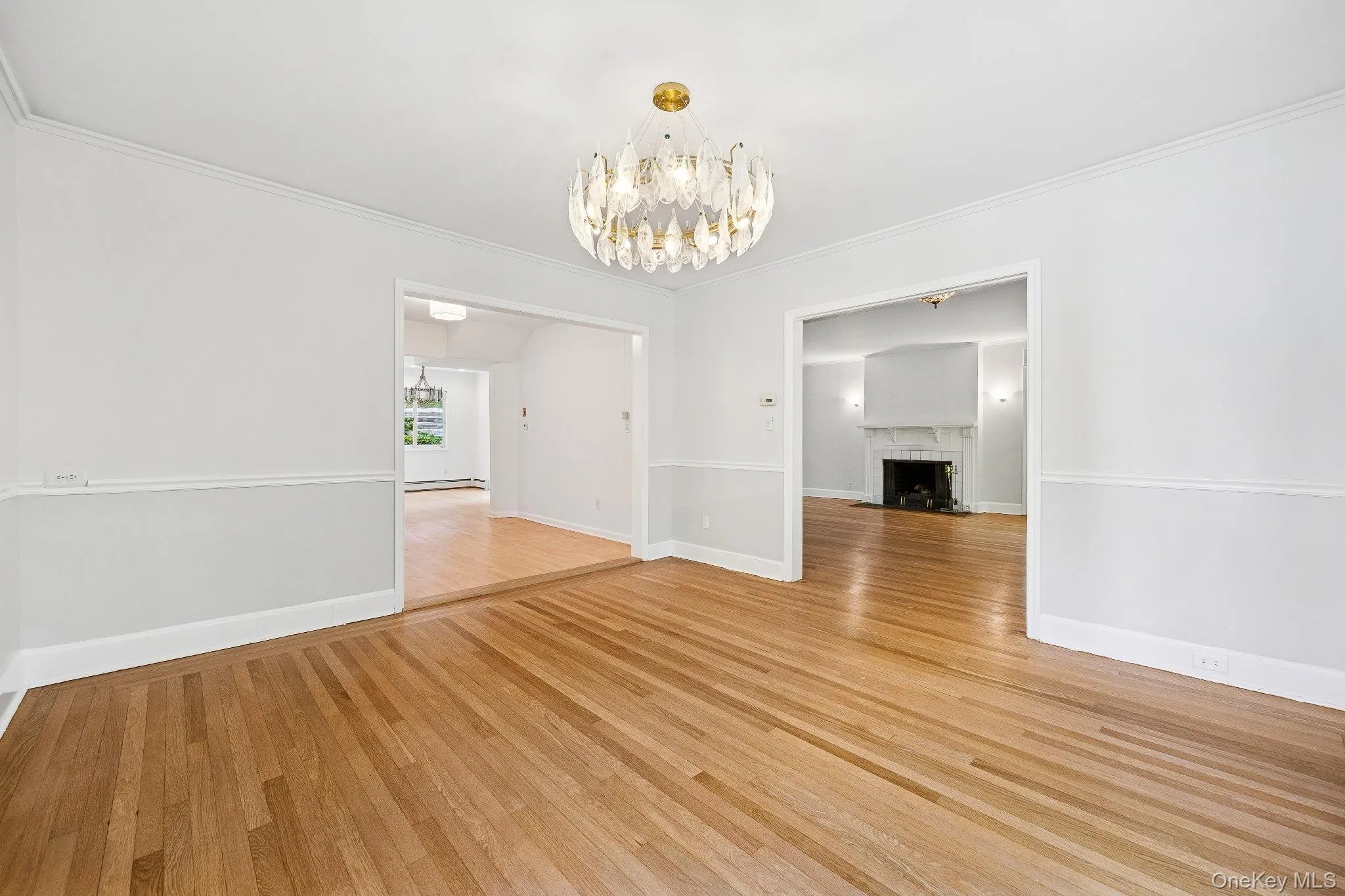 Dinning room featuring light wood-style flooring, a chandelier, a fireplace, and ornamental molding Dinning room featuring light wood-style flooring, a chandelier, a fireplace, and ornamental molding