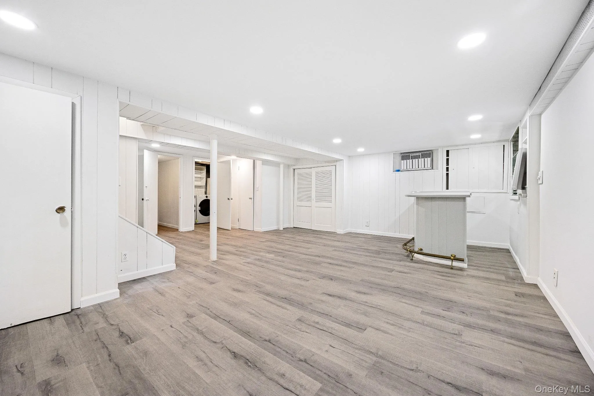 Finished below grade area with recessed lighting, light wood-style flooring, and washer / dryer Finished below grade area with recessed lighting, light wood-style flooring, and washer / dryer