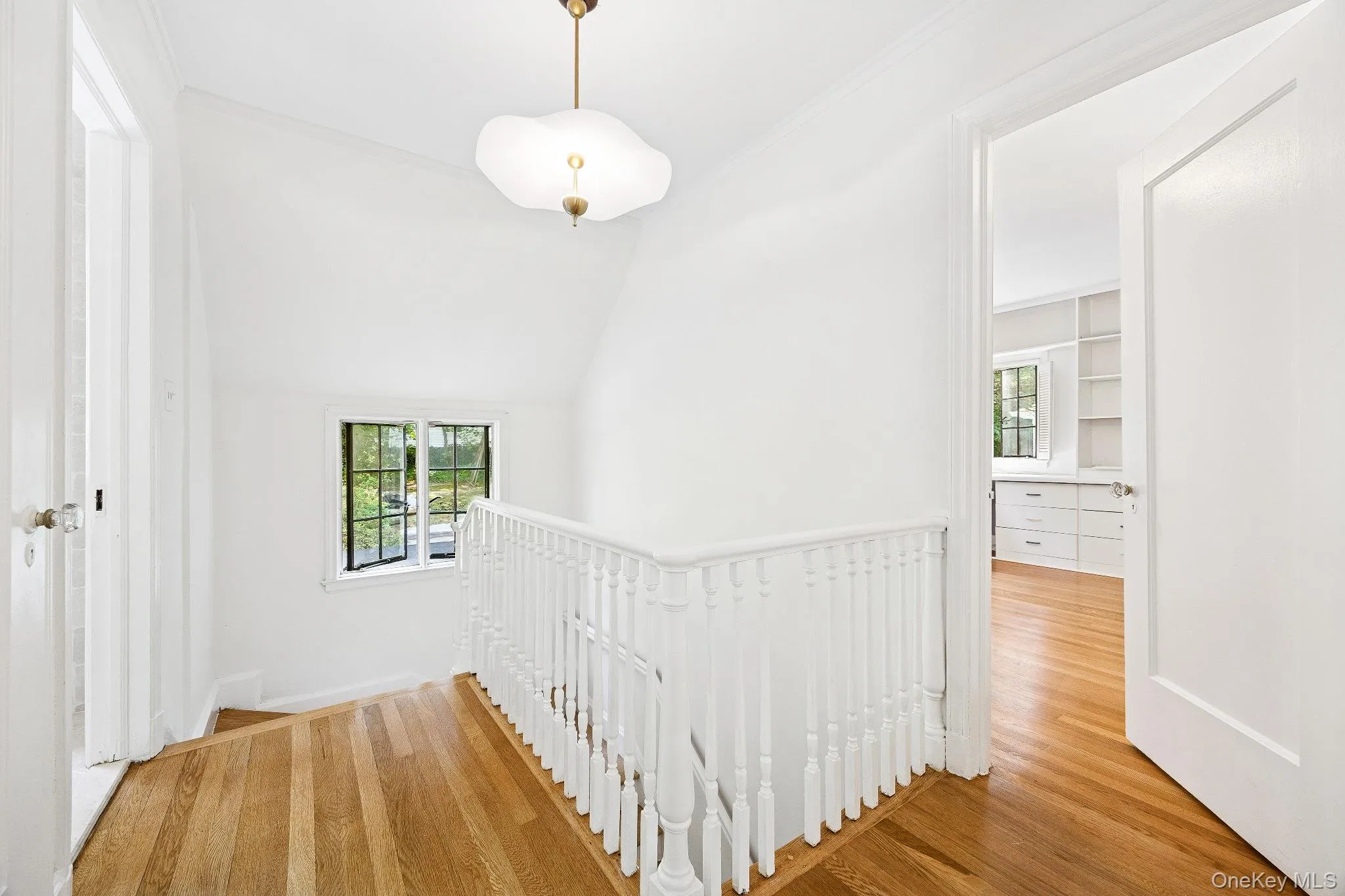 Hallway featuring an upstairs landing, crown molding, and wood finished floors Hallway featuring an upstairs landing, crown molding, and wood finished floors