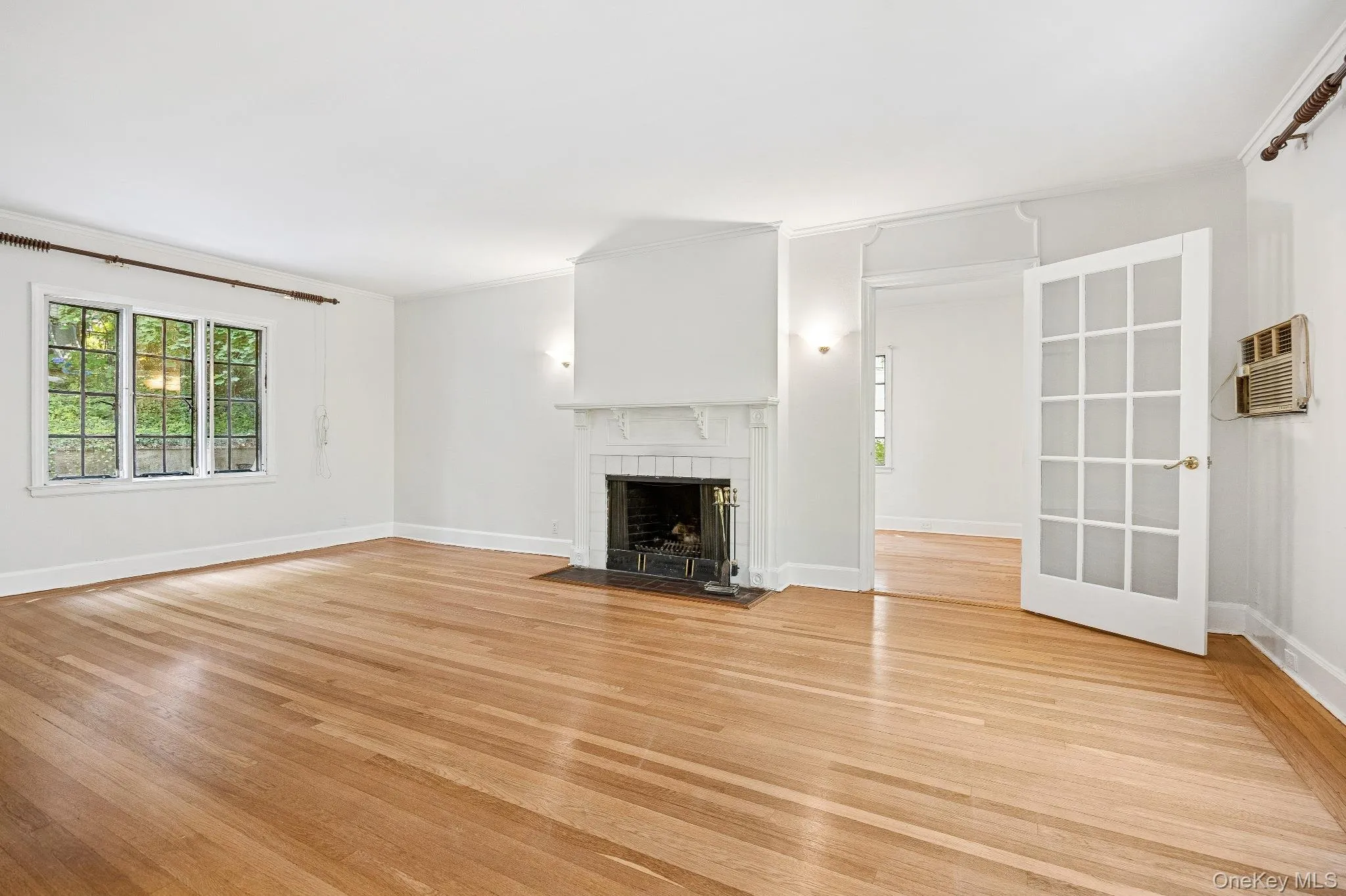 living room featuring light wood-style floors, crown molding, a tile fireplace living room featuring light wood-style floors, crown molding, a tile fireplace