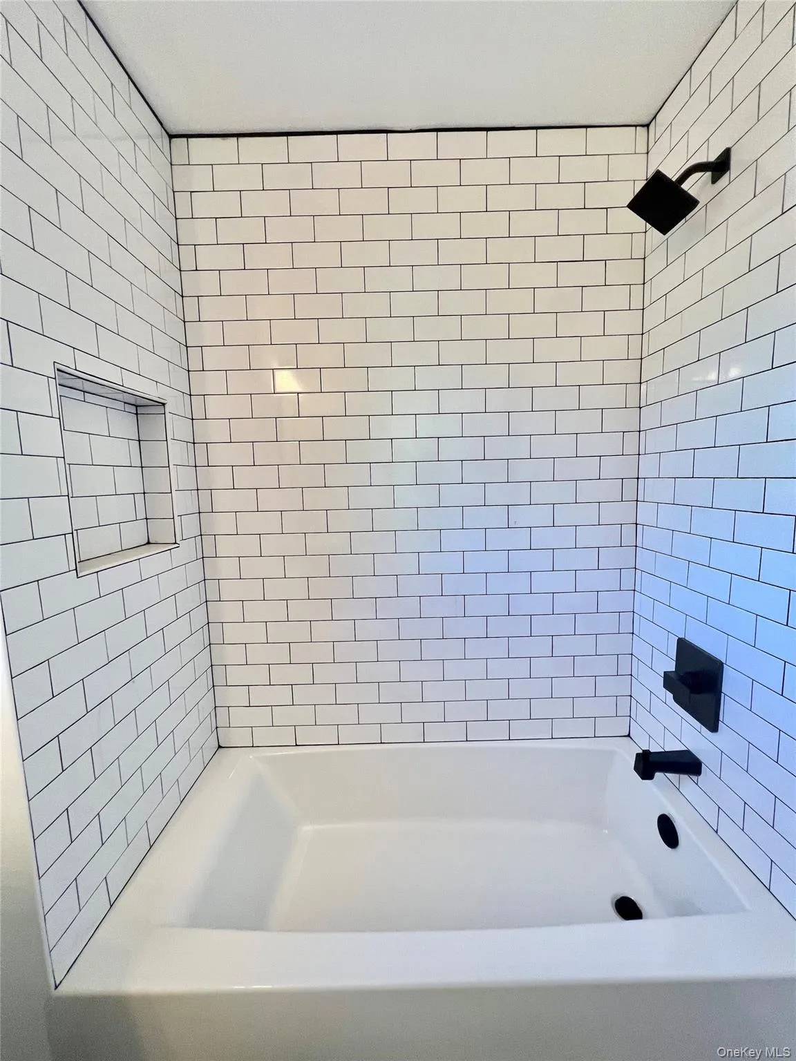 White subway tile surround with black grout and a deep soaking tub White subway tile surround with black grout and a deep soaking tub