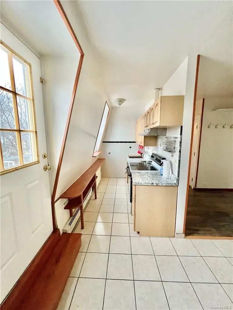 Functional kitchen space featuring light wood-finish cabinetry, granite-style countertops, and a full-size range Functional kitchen space featuring light wood-finish cabinetry, granite-style countertops, and a full-size range