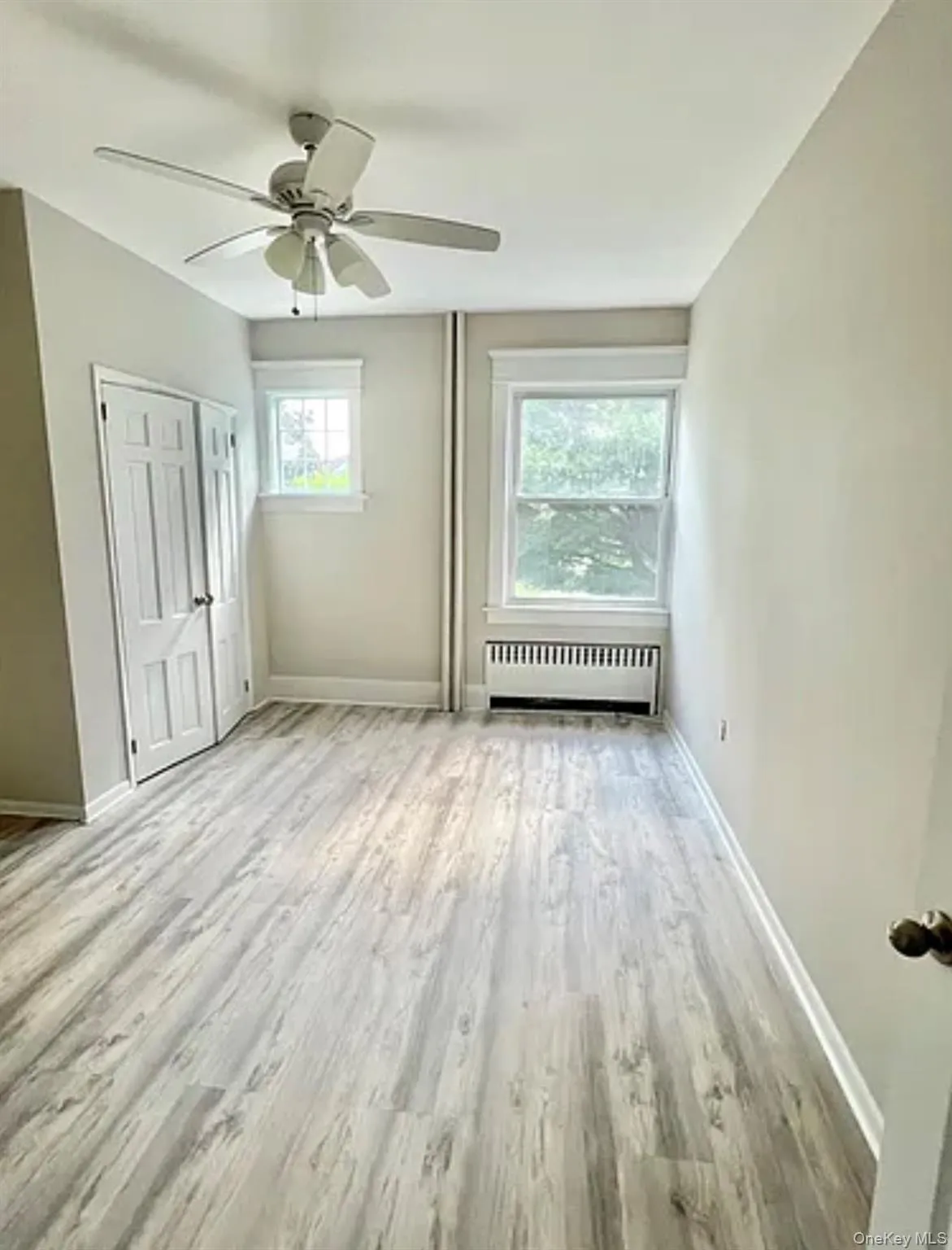 Spacious 2nd bedroom featuring light wood-finish flooring, a ceiling fan, and two windows Spacious 2nd bedroom featuring light wood-finish flooring, a ceiling fan, and two windows