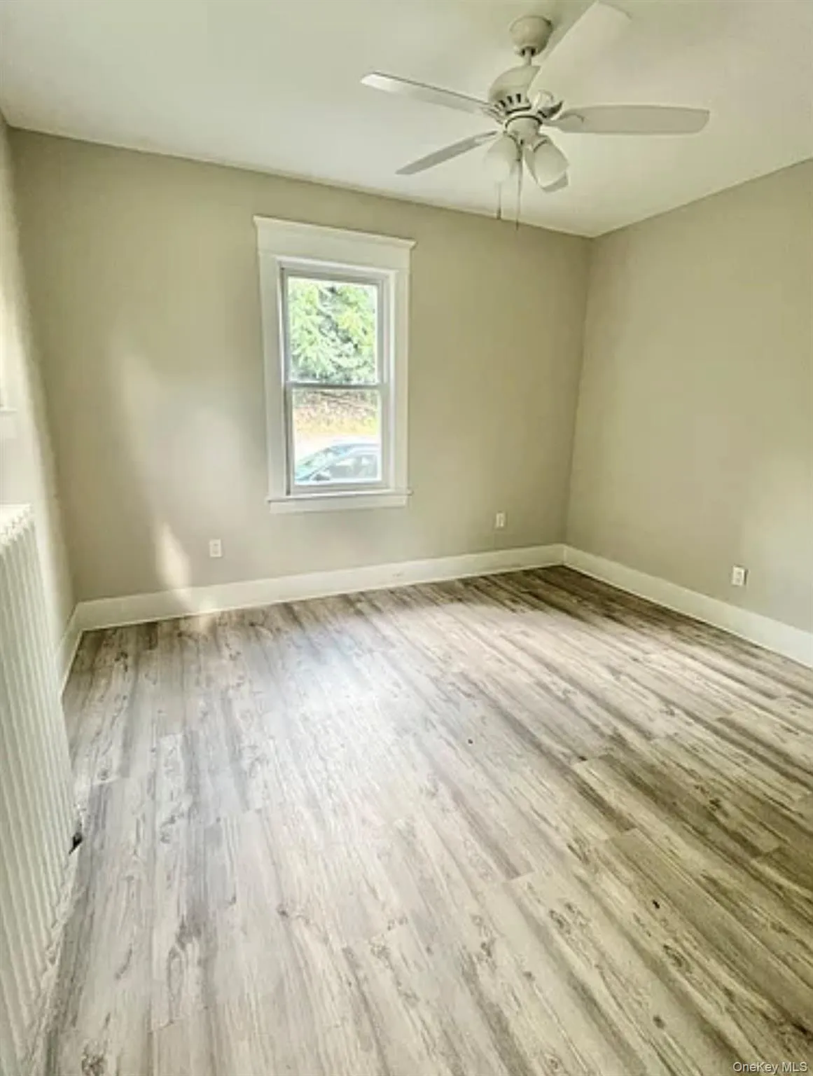 main bedroom featuring light wood-finish flooring, a white trim window, a ceiling fan with integrated lighting, and neutral wall paint main bedroom featuring light wood-finish flooring, a white trim window, a ceiling fan with integrated lighting, and neutral wall paint