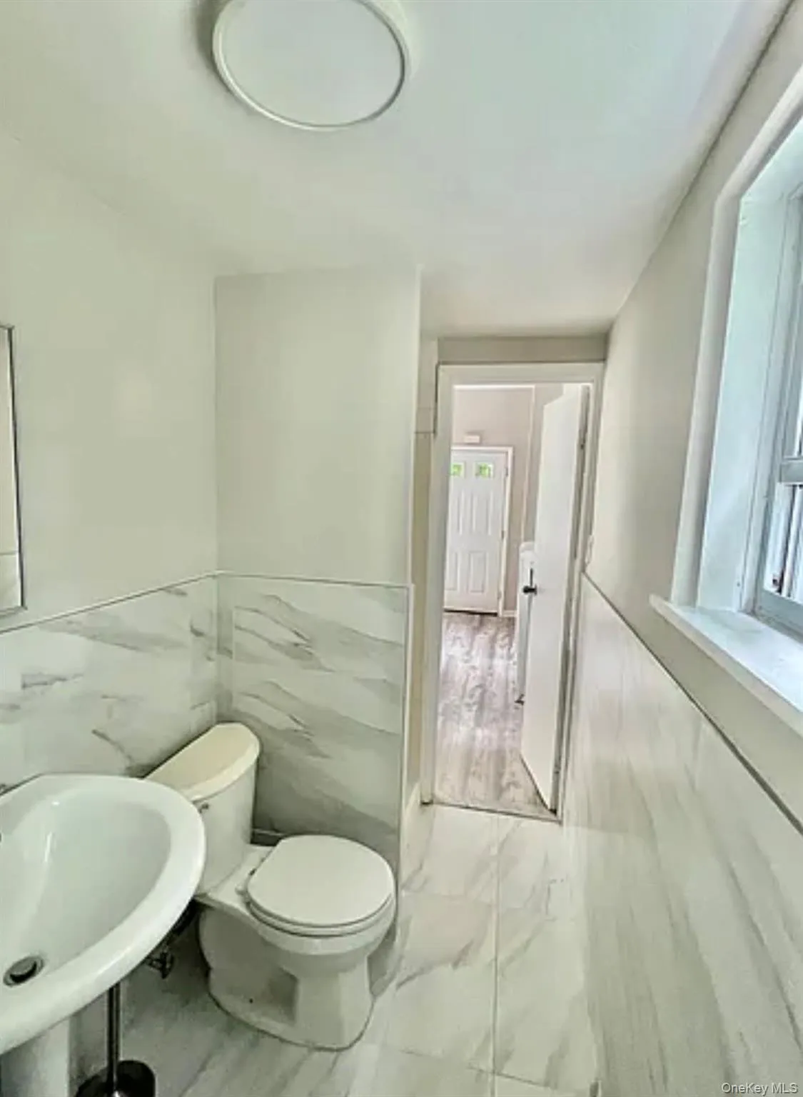 Bathroom featuring a pedestal sink, toilet, and white tile flooring Bathroom featuring a pedestal sink, toilet, and white tile flooring