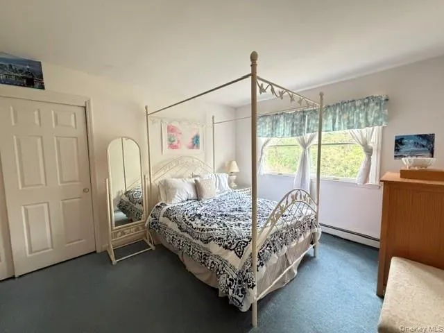 Bedroom featuring wall-to-wall carpeting, white painted walls, and a large window with natural light Bedroom featuring wall-to-wall carpeting, white painted walls, and a large window with natural light