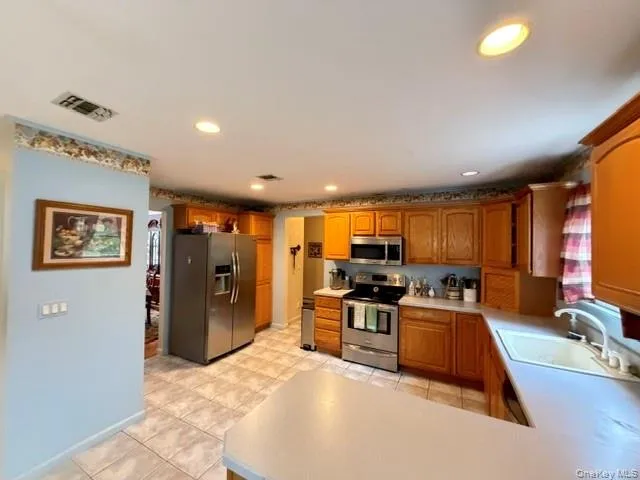 Kitchen with light wood cabinetry, stainless steel appliances, and recessed lighting Kitchen with light wood cabinetry, stainless steel appliances, and recessed lighting