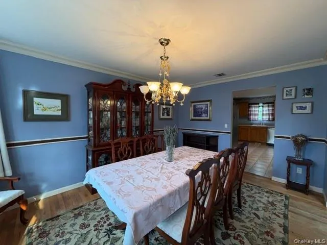 Dining area featuring wood-finish flooring, a decorative area rug, and a brass chandelier Dining area featuring wood-finish flooring, a decorative area rug, and a brass chandelier