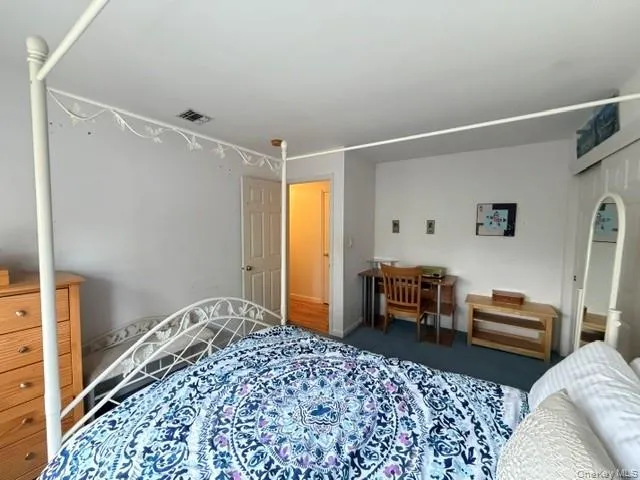 Bedroom featuring a white six-panel door, blue carpet flooring, and white walls Bedroom featuring a white six-panel door, blue carpet flooring, and white walls
