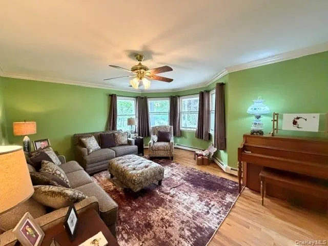 Hardwood flooring throughout featuring a bay window, crown molding, and a ceiling fan with light fixture Hardwood flooring throughout featuring a bay window, crown molding, and a ceiling fan with light fixture