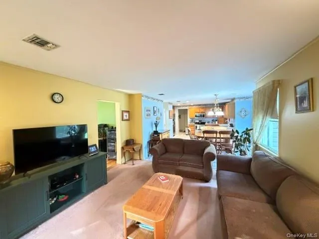 Spacious living area featuring light yellow wall paint and a light-colored carpet Spacious living area featuring light yellow wall paint and a light-colored carpet