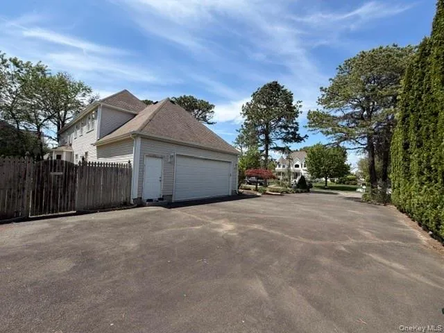 Property exterior featuring a two-car garage with a side entry door, light-colored siding, and a gabled roof Property exterior featuring a two-car garage with a side entry door, light-colored siding, and a gabled roof