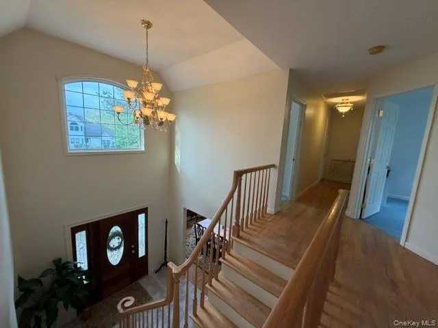 Two-story foyer featuring an arched transom window, a multi-tiered chandelier, and a dark wood entry door with decorative glass inserts Two-story foyer featuring an arched transom window, a multi-tiered chandelier, and a dark wood entry door with decorative glass inserts