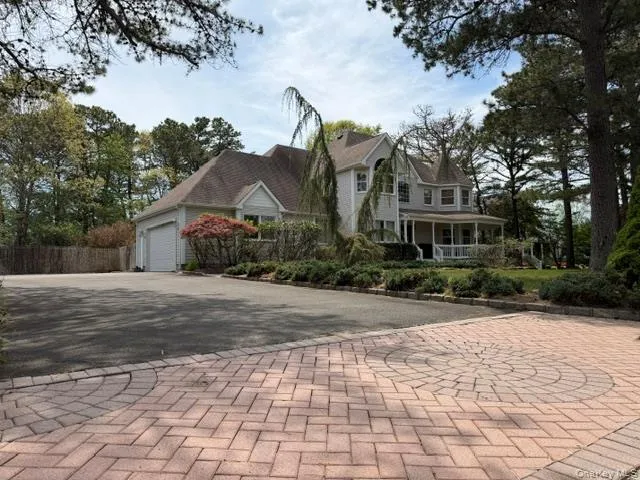 Two-story residence featuring a covered front porch, an attached garage, and a paver stone driveway with a circular inlay Two-story residence featuring a covered front porch, an attached garage, and a paver stone driveway with a circular inlay