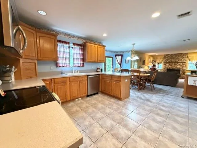 Kitchen featuring wood cabinetry, light-toned countertops, tile flooring, and stainless steel appliances Kitchen featuring wood cabinetry, light-toned countertops, tile flooring, and stainless steel appliances