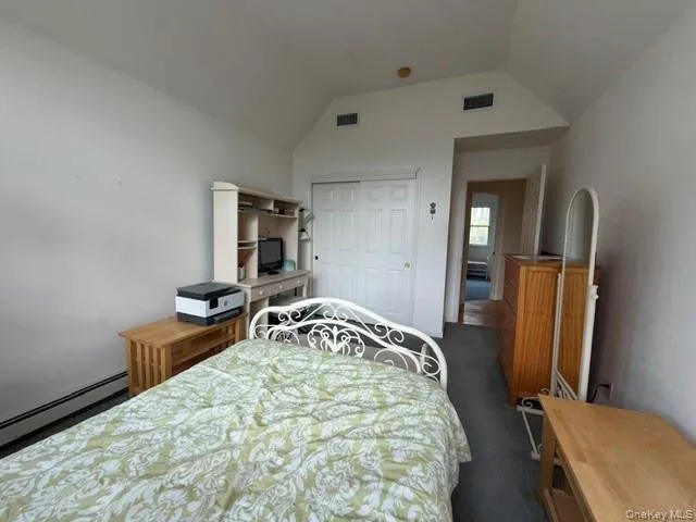 Bedroom featuring vaulted ceilings, wall-to-wall carpeting, and baseboard heating Bedroom featuring vaulted ceilings, wall-to-wall carpeting, and baseboard heating
