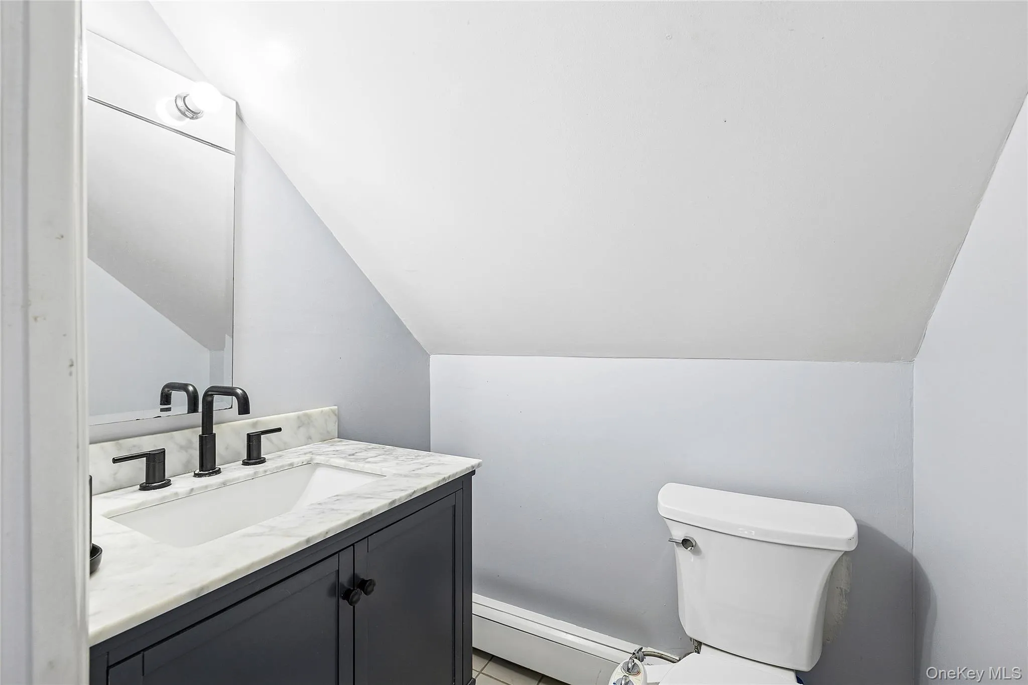 Vanity with a white rectangular undermount sink, a marble-finish countertop, and a matte black faucet Vanity with a white rectangular undermount sink, a marble-finish countertop, and a matte black faucet