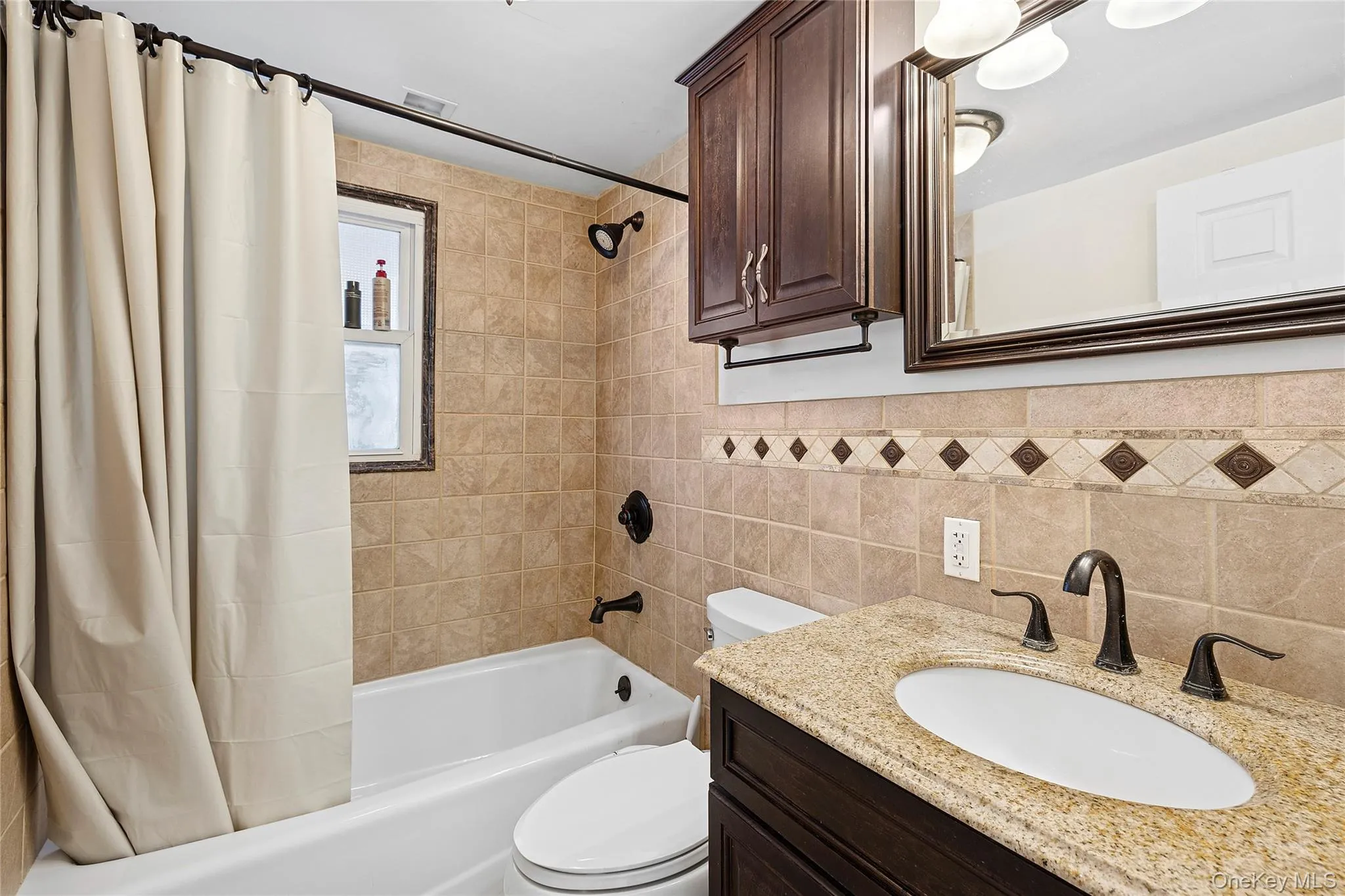 Bathroom featuring a built-in vanity with a granite-style countertop, undermount sink, and dark bronze-finish fixtures Bathroom featuring a built-in vanity with a granite-style countertop, undermount sink, and dark bronze-finish fixtures