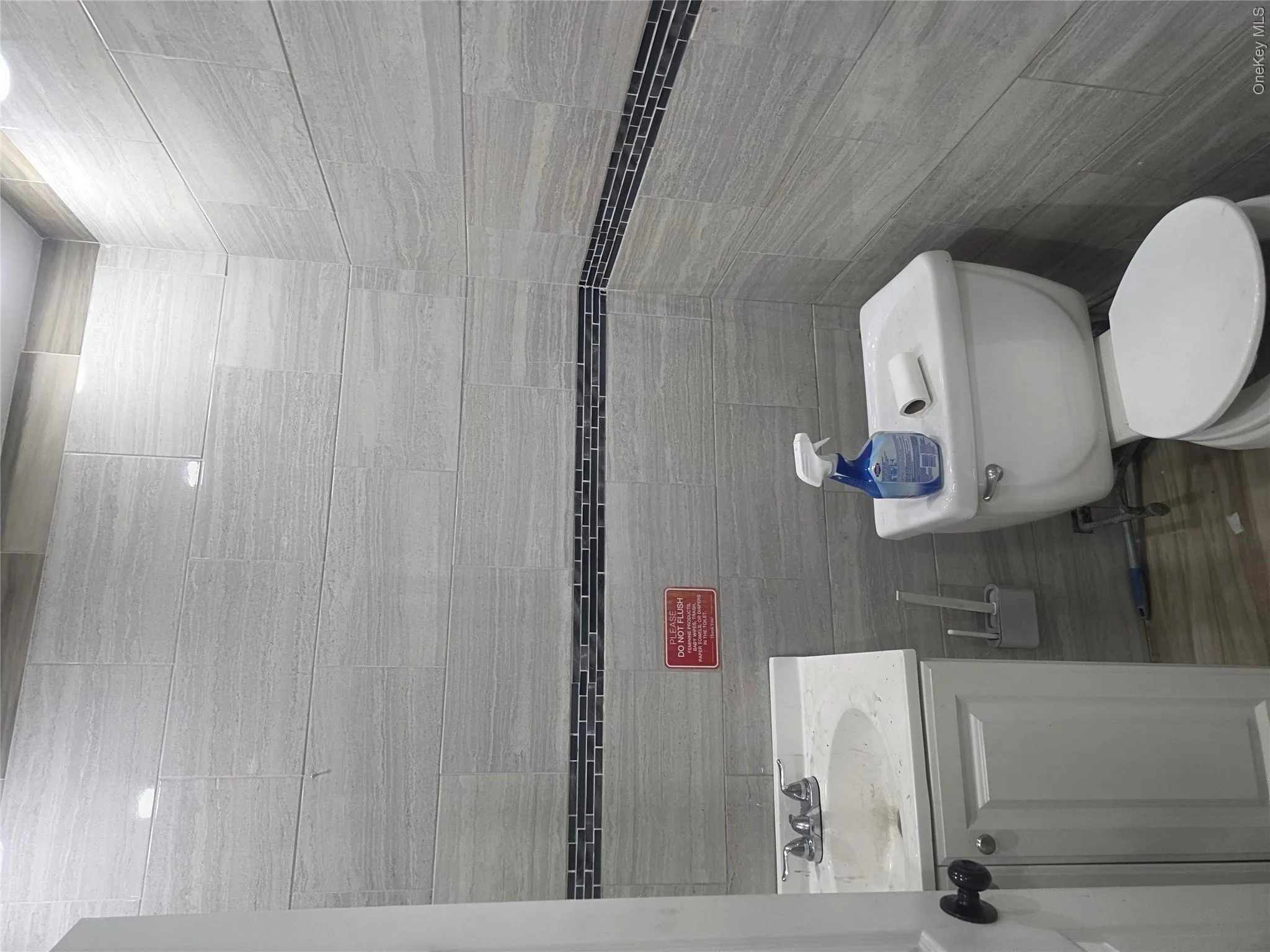 Bathroom featuring light gray horizontal tile walls with a dark mosaic accent band Bathroom featuring light gray horizontal tile walls with a dark mosaic accent band