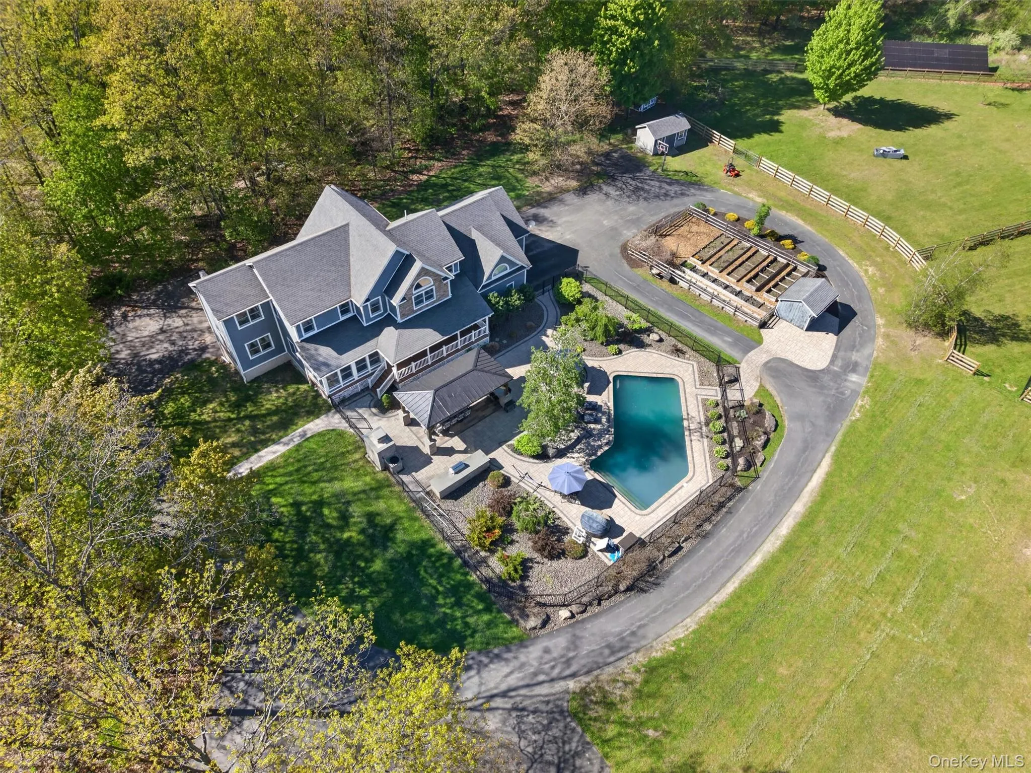 An aerial view highlighting the home’s expansive setting including beautiful pool and patio, mature gardens, outbuildings, and room to roam! An aerial view highlighting the home’s expansive setting including beautiful pool and patio, mature gardens, outbuildings, and room to roam!