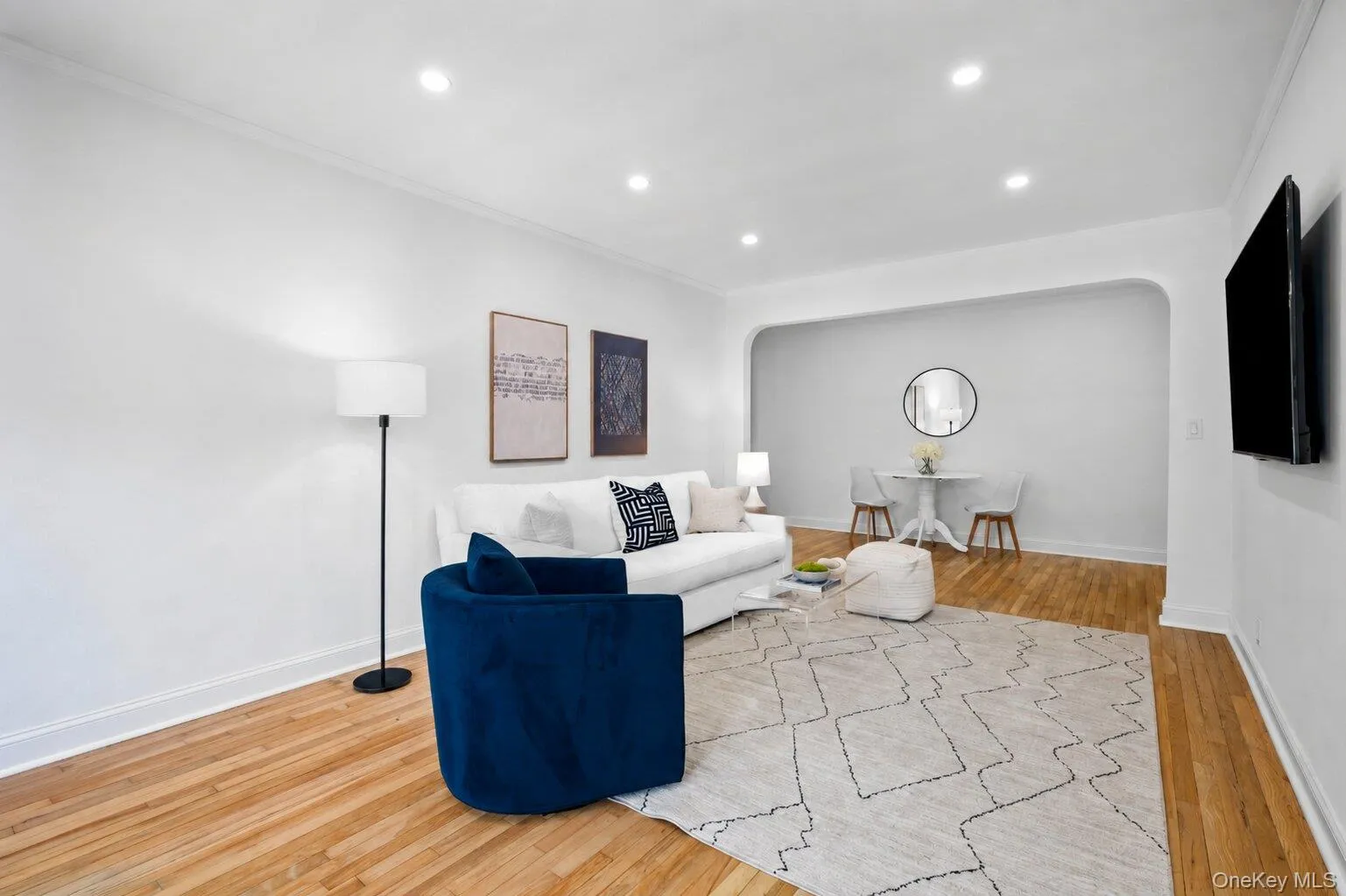 Spacious living room with hardwood floors, recessed lighting, and an arched opening to a defined dining area. Spacious living room with hardwood floors, recessed lighting, and an arched opening to a defined dining area.
