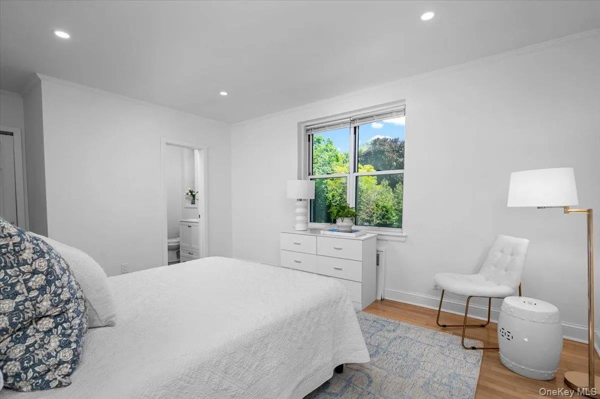 Comfortable bedroom features tree top views, hardwood floors, recessed lighting, and ensuite updated bath Comfortable bedroom features tree top views, hardwood floors, recessed lighting, and ensuite updated bath