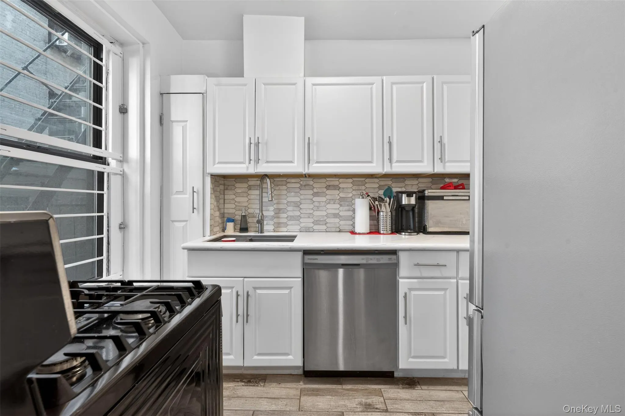 Kitchen featuring white cabinetry, light-toned countertop, and stainless steel dishwasher Kitchen featuring white cabinetry, light-toned countertop, and stainless steel dishwasher