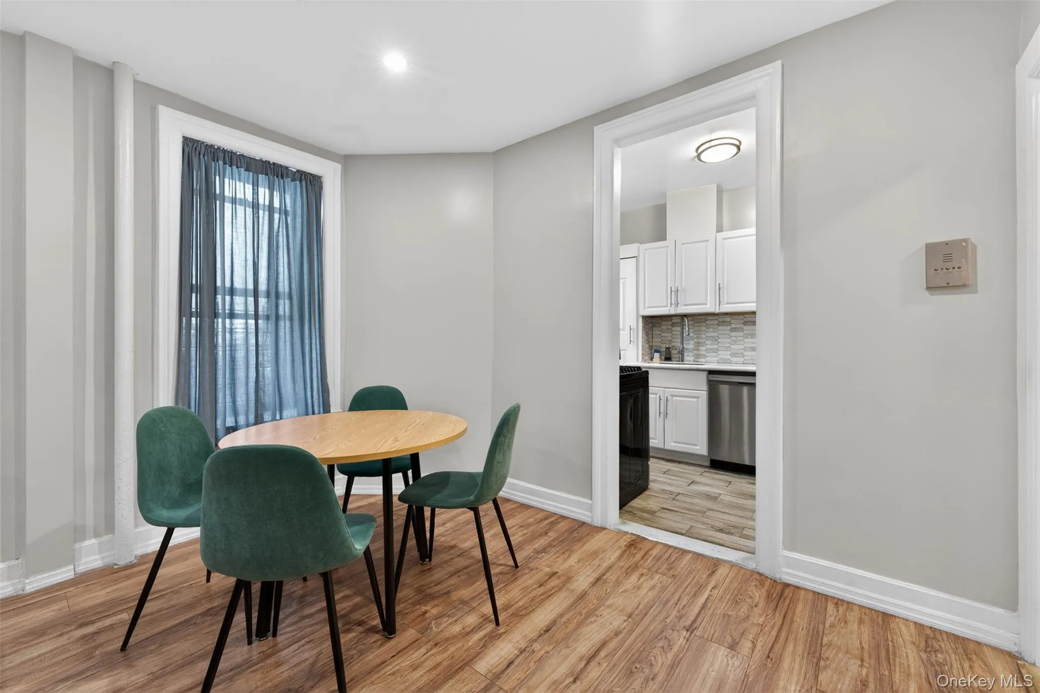 Dining area featuring wood-finish flooring, white baseboards, and light gray walls Dining area featuring wood-finish flooring, white baseboards, and light gray walls