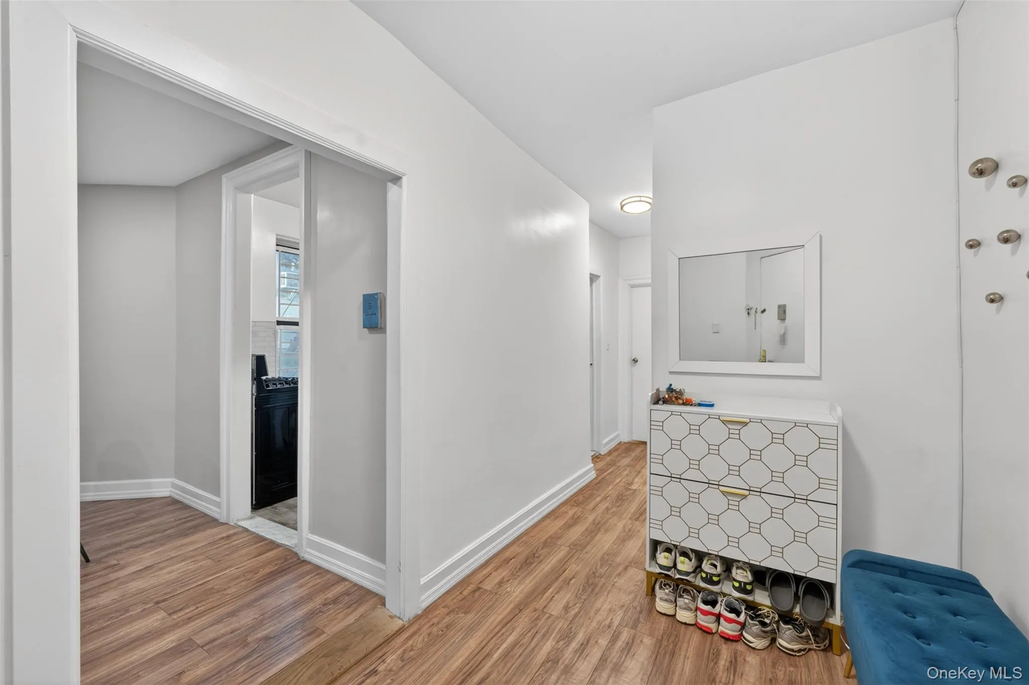 Hallway featuring wood-finish flooring, white baseboards, and light-toned walls Hallway featuring wood-finish flooring, white baseboards, and light-toned walls