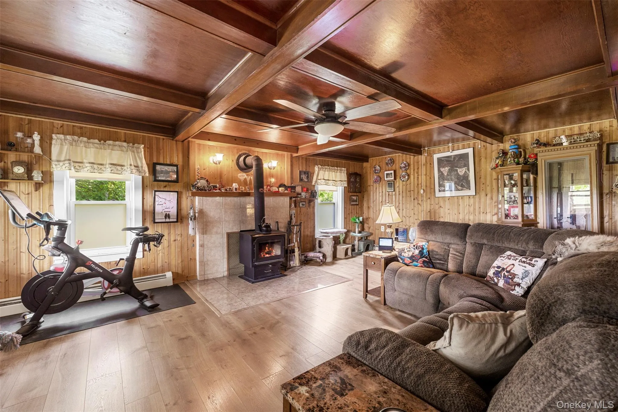 Living area with wood stove, ceiling fan, and coffered ceiling Living area with wood stove, ceiling fan, and coffered ceiling