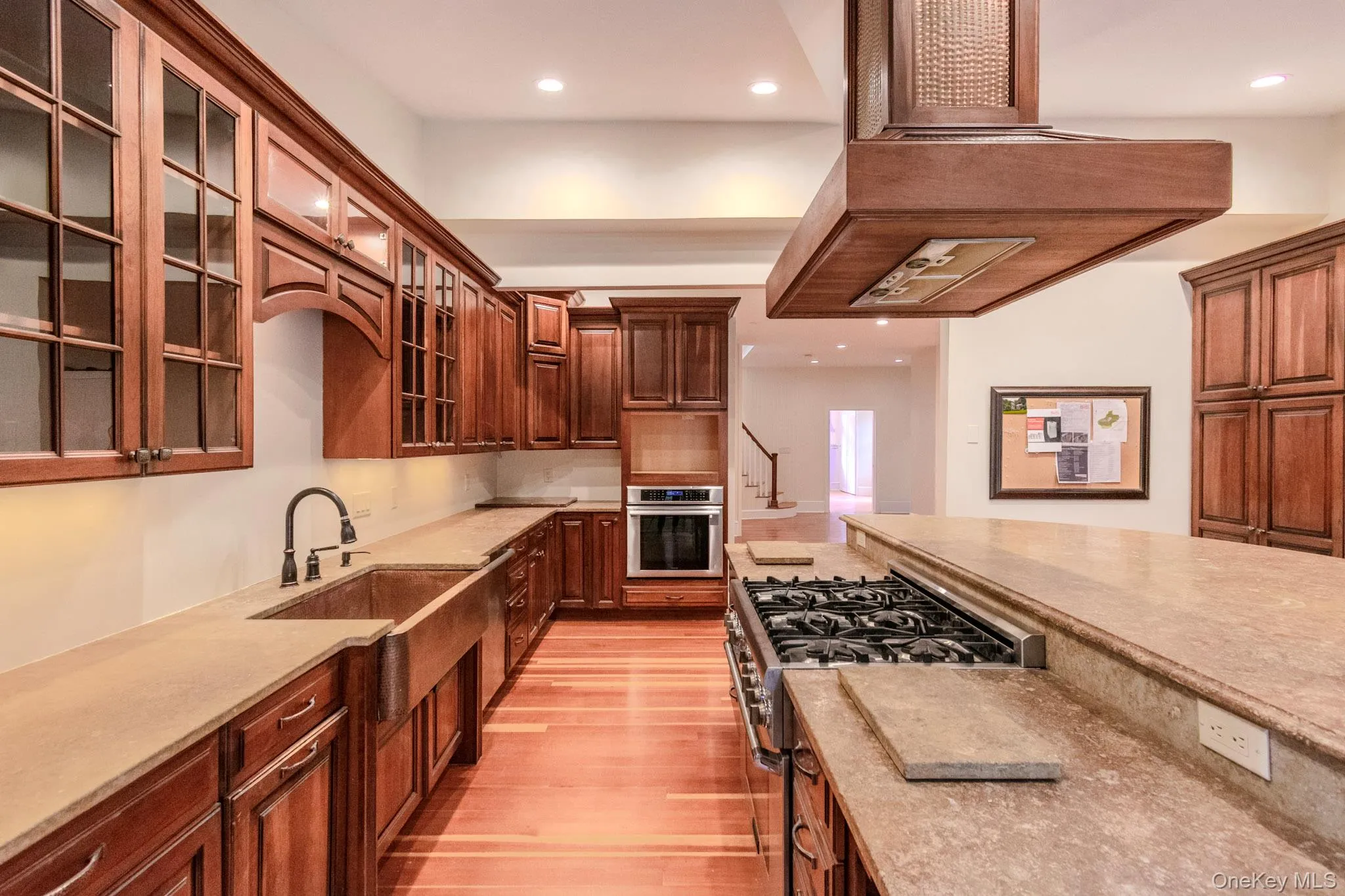 Kitchen featuring sink, stainless steel appliances, light stone counters, light hardwood / wood-style floors, and custom range hood Kitchen featuring sink, stainless steel appliances, light stone counters, light hardwood / wood-style floors, and custom range hood