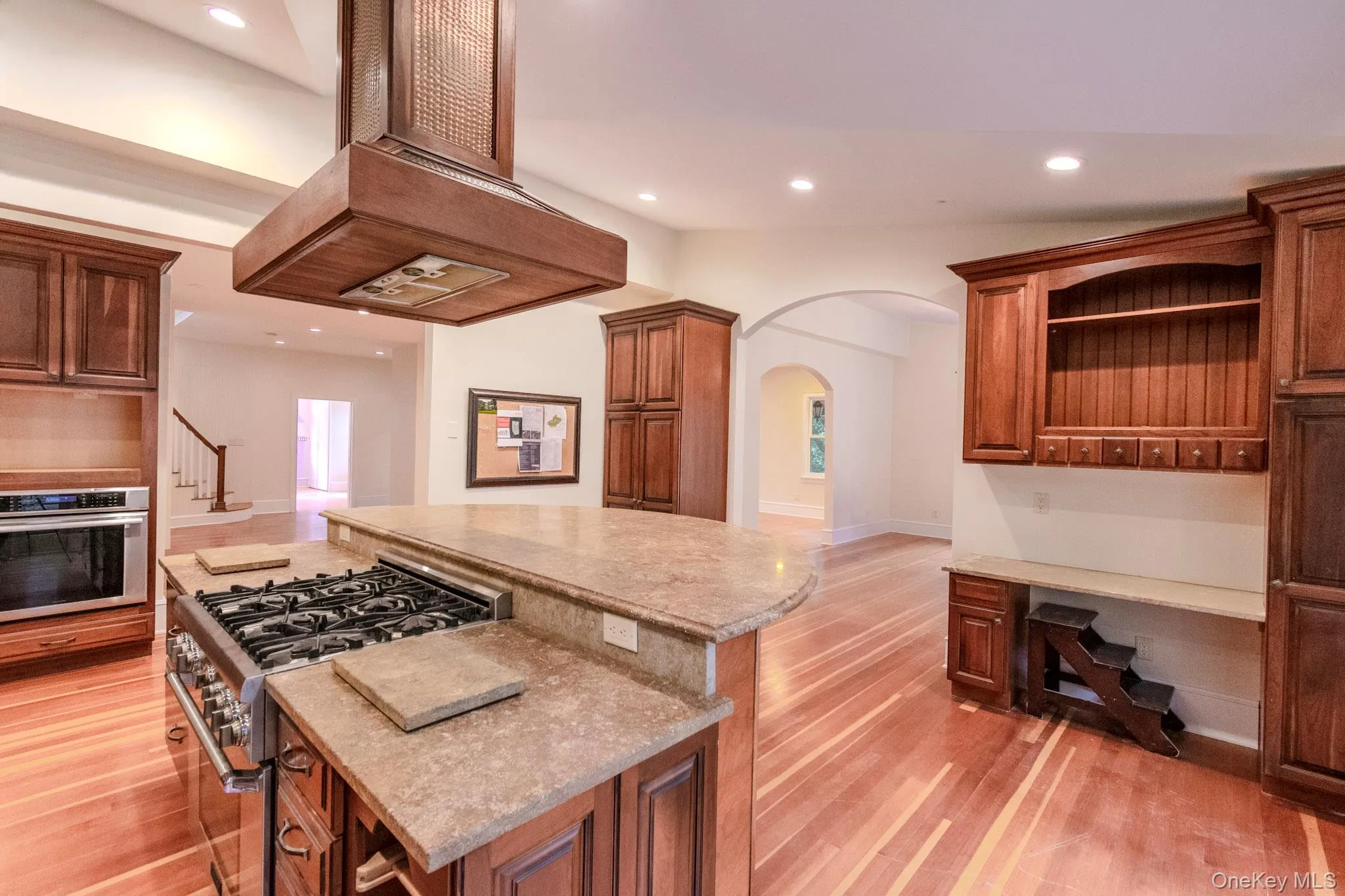 Kitchen with a kitchen island, stainless steel appliances, custom range hood, and light hardwood / wood-style floors Kitchen with a kitchen island, stainless steel appliances, custom range hood, and light hardwood / wood-style floors