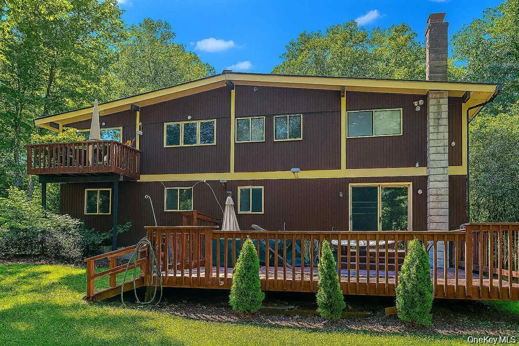 Multi-level exterior featuring brown vertical siding, yellow trim, and multiple windows Multi-level exterior featuring brown vertical siding, yellow trim, and multiple windows
