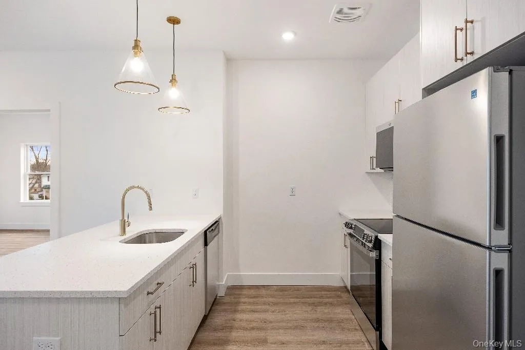 Kitchen featuring kitchen peninsula, appliances with stainless steel finishes, light wood-type flooring, sink, and hanging light fixtures Kitchen featuring kitchen peninsula, appliances with stainless steel finishes, light wood-type flooring, sink, and hanging light fixtures