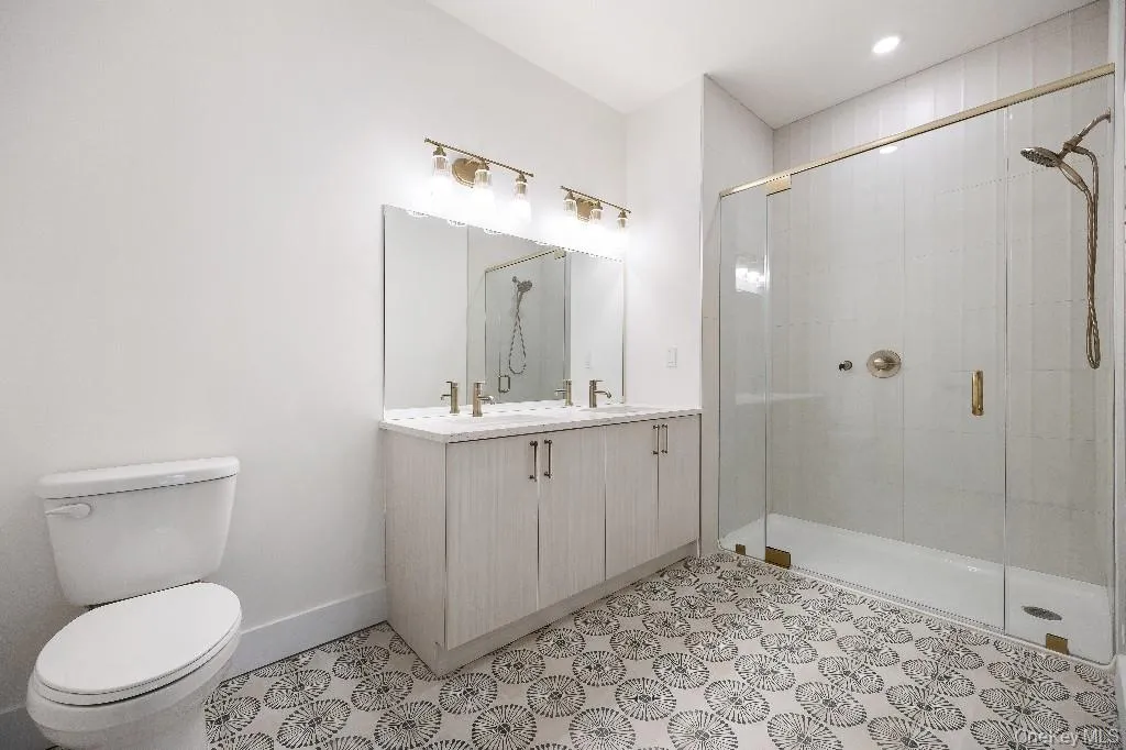 Bathroom featuring vanity, toilet, and a shower with shower door Bathroom featuring vanity, toilet, and a shower with shower door