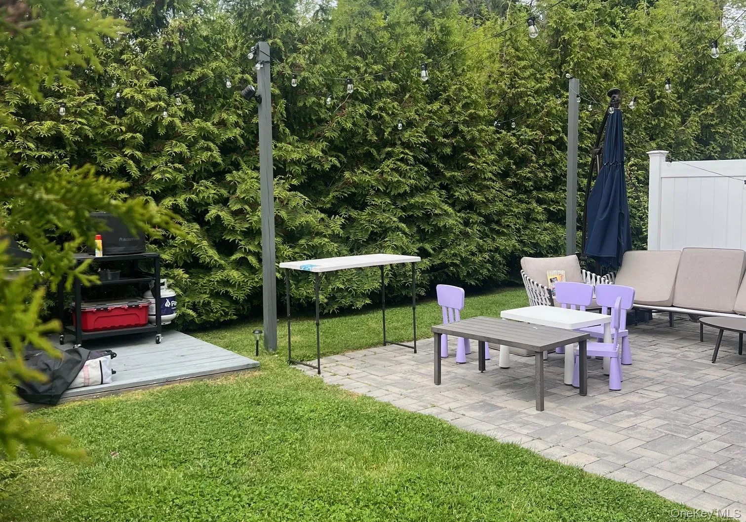 Paver patio with privacy landscaping and a white fence Paver patio with privacy landscaping and a white fence