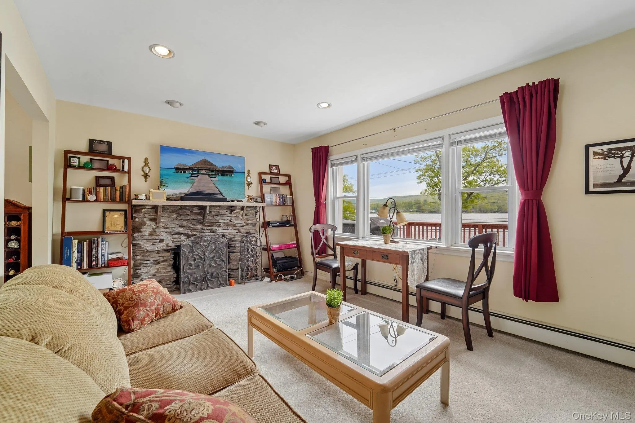 Living room with wood burning fireplace and lake views. Living room with wood burning fireplace and lake views.